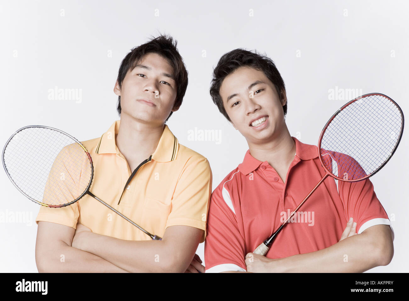 Portrait of two young men holding badminton rackets and smiling Stock Photo