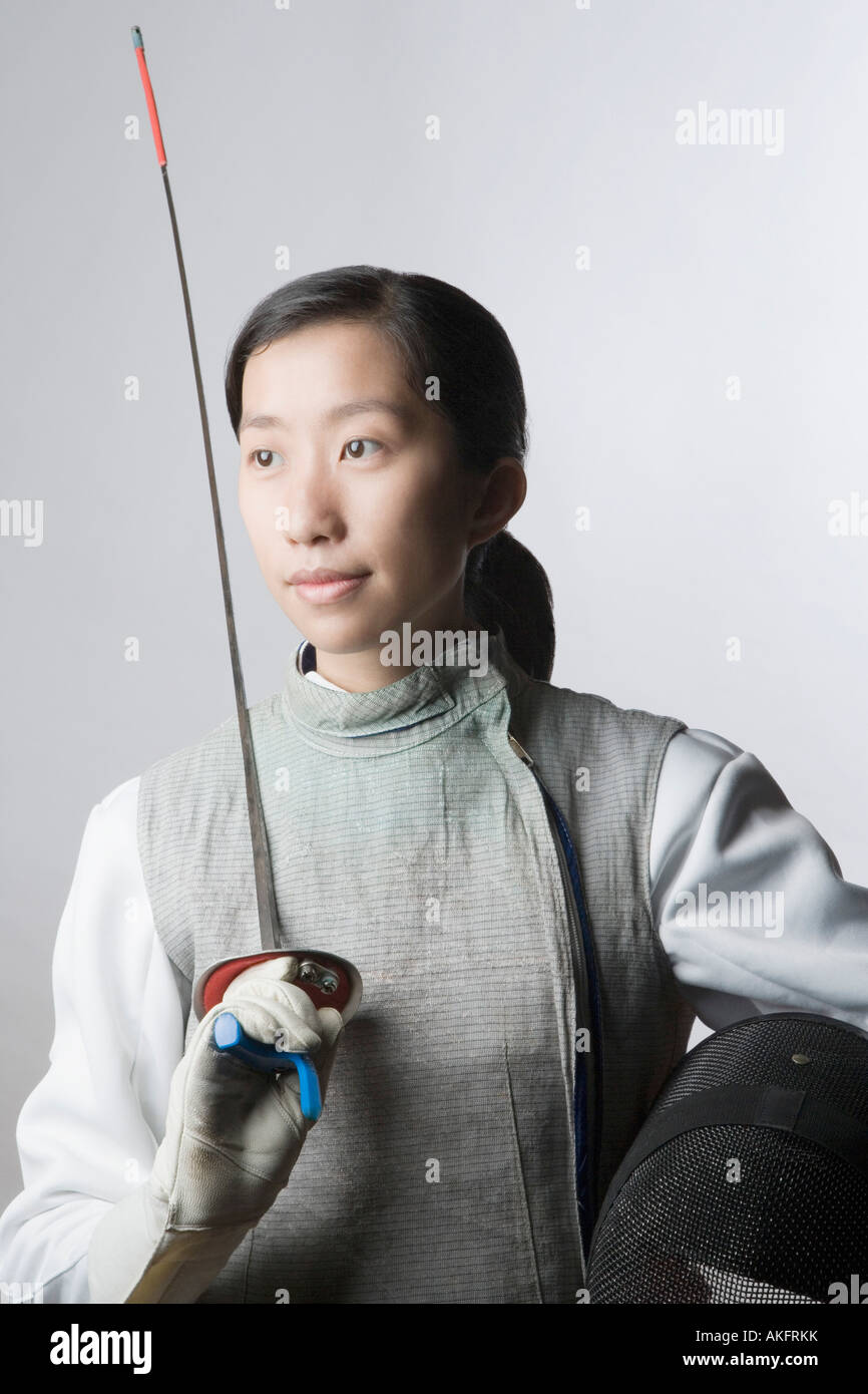 Closeup of a female fencer holding a sword and a fencing mask Stock