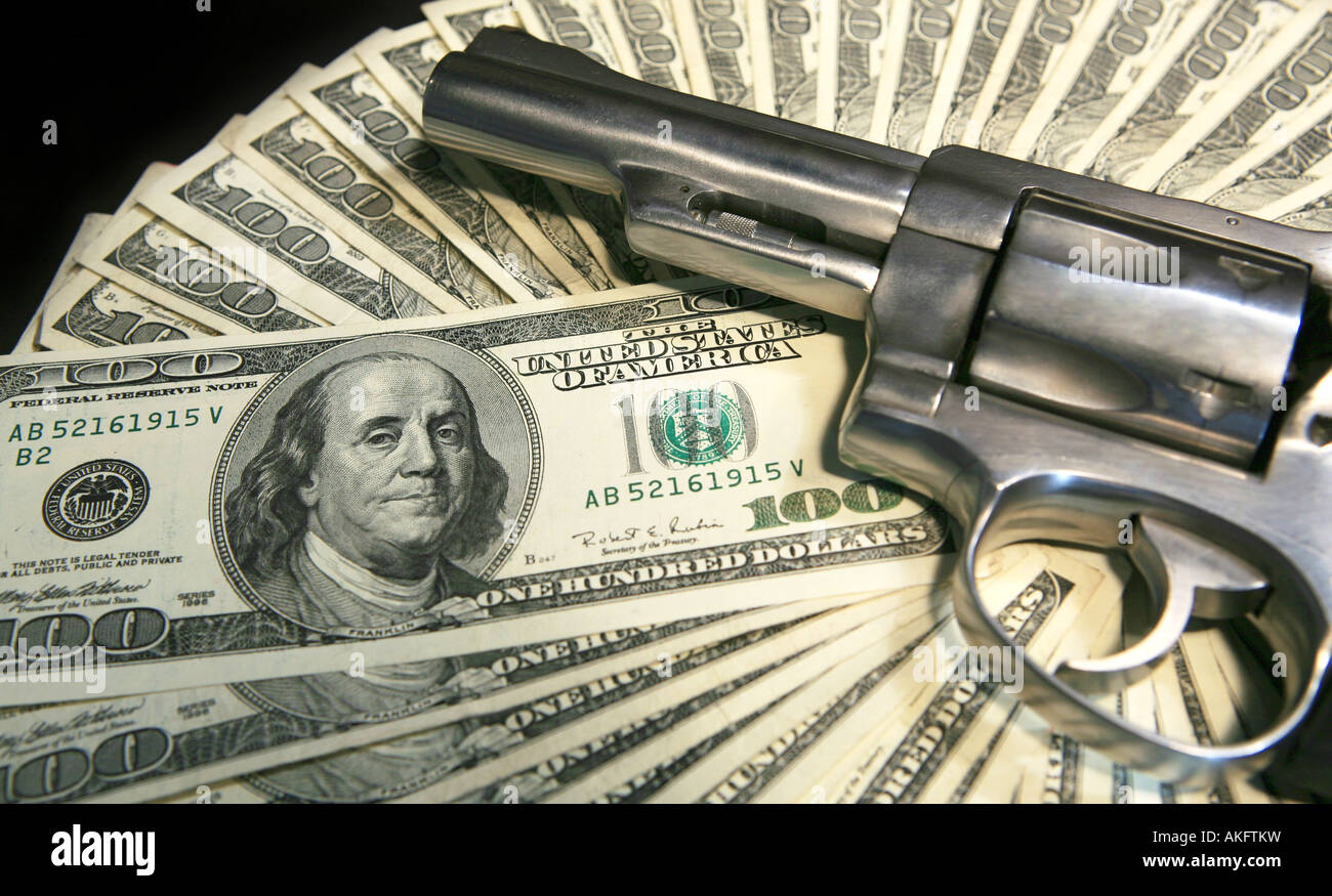 Hand gun on top on one hundred dollar bills isolated on white background Stock Photo