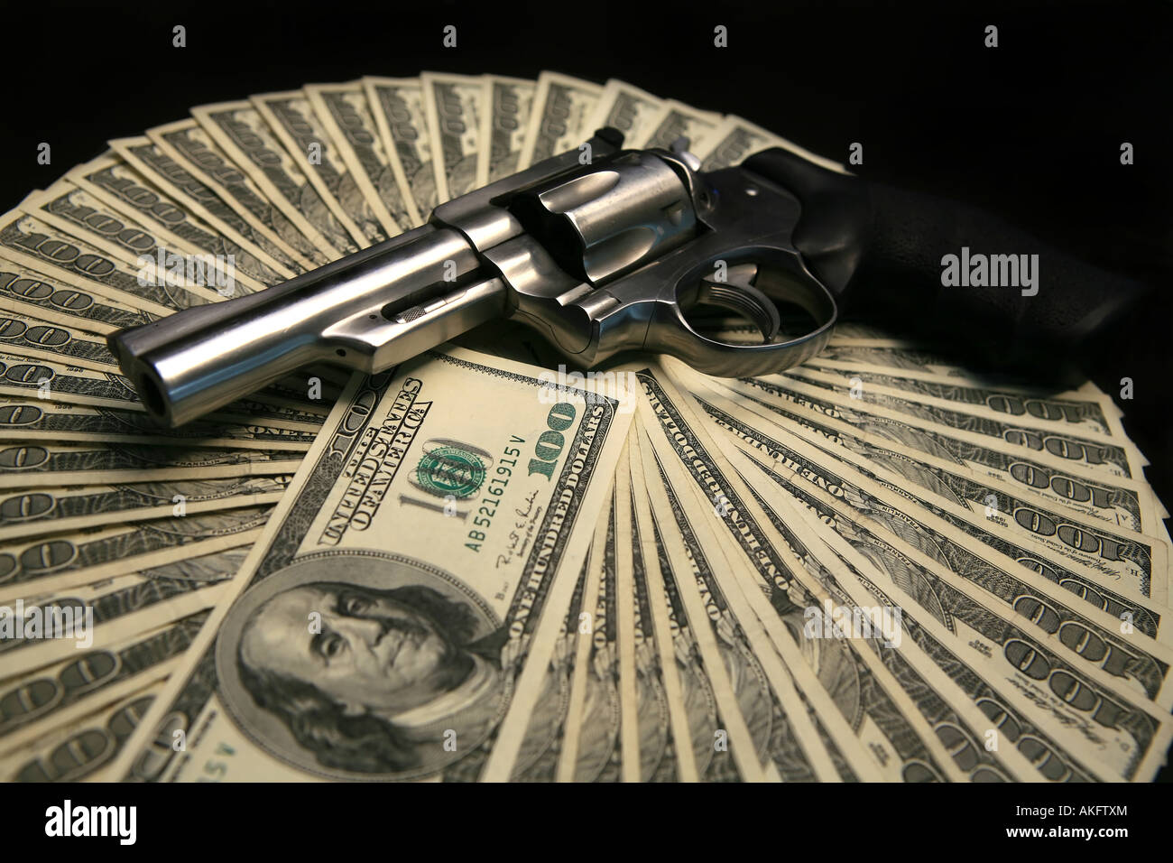 Hand gun on top on one hundred dollar bills isolated on white background Stock Photo