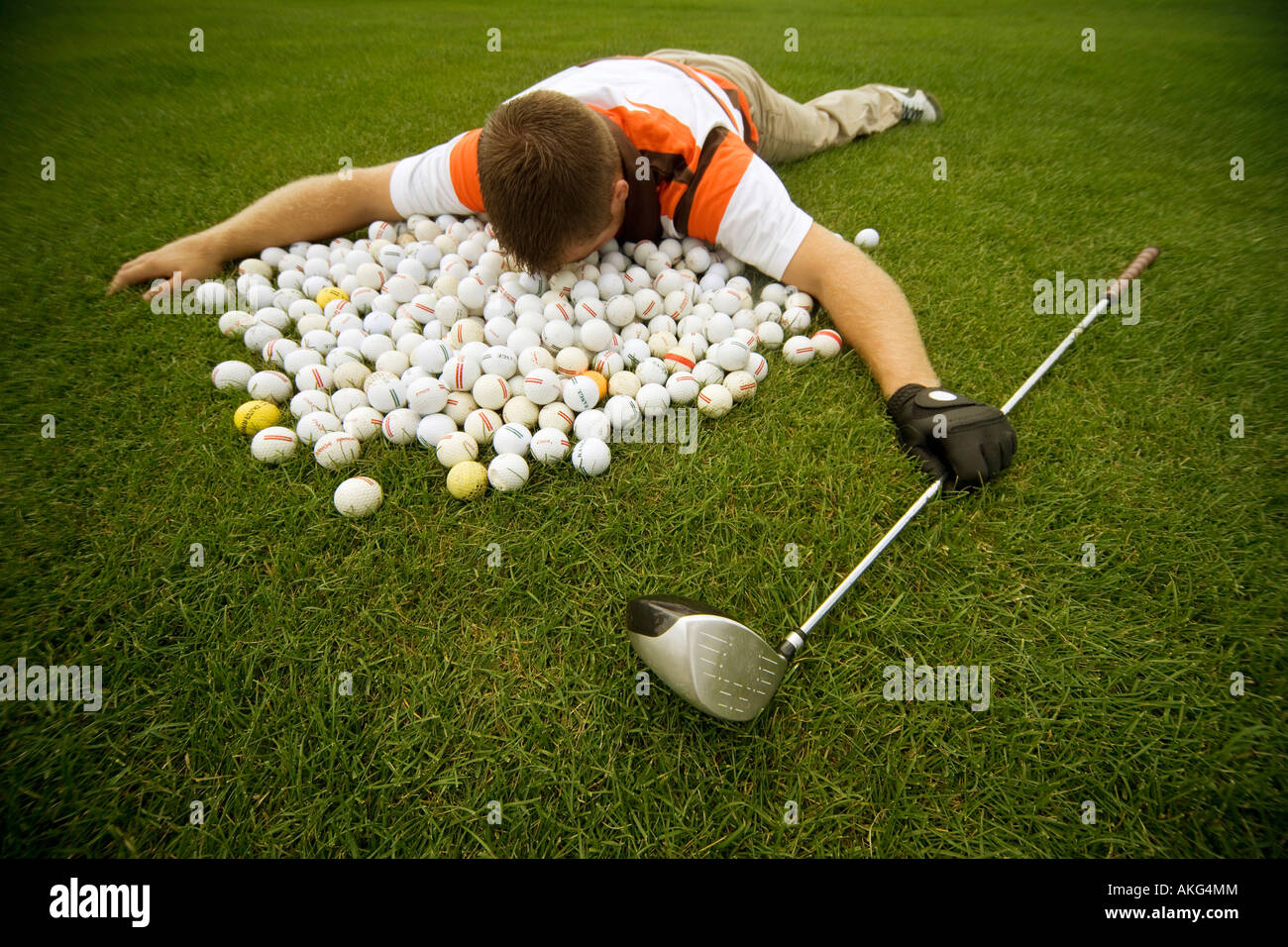 Man lying in pile of golf balls Stock Photo