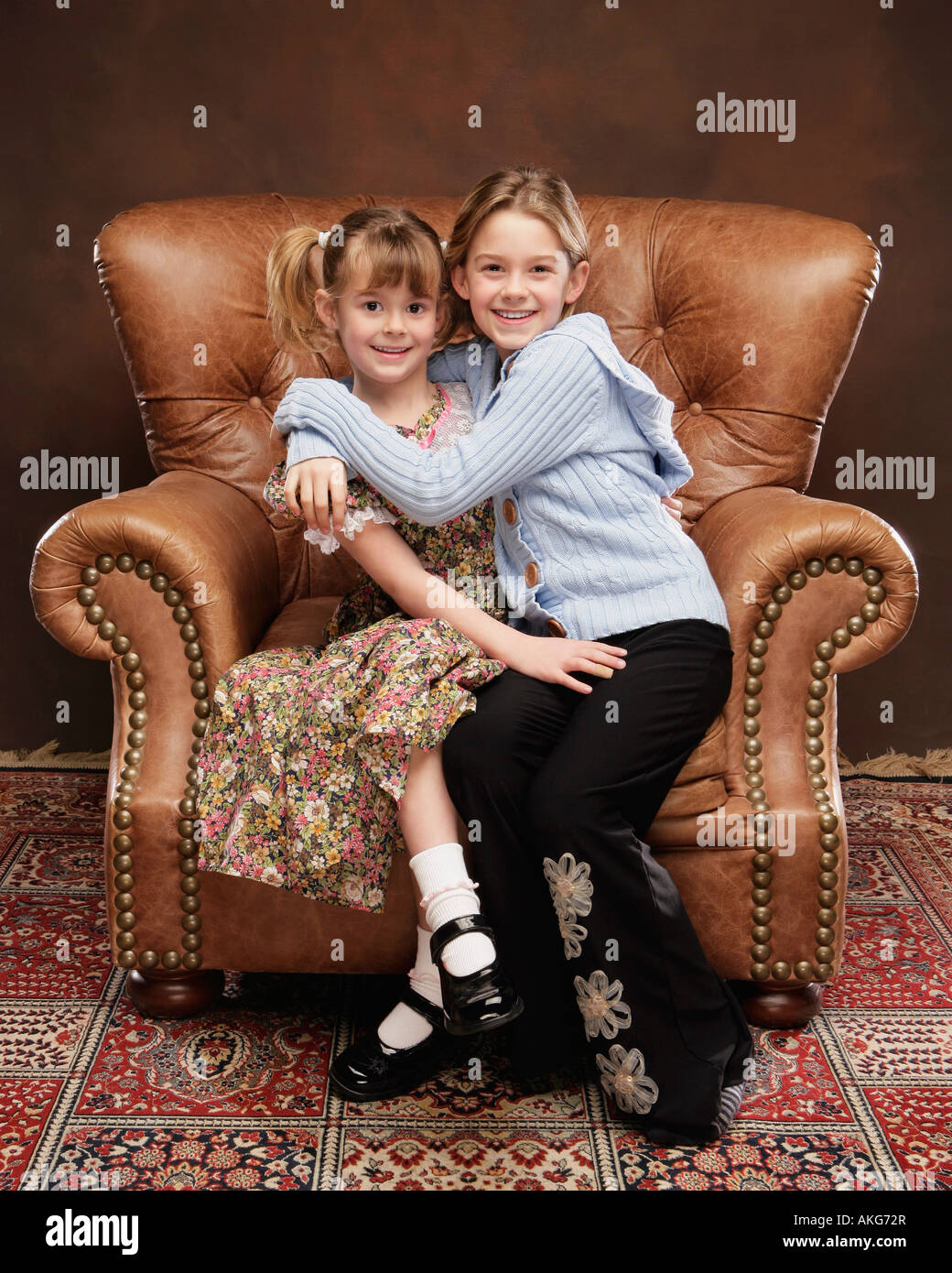 Two girls sitting in armchair Stock Photo