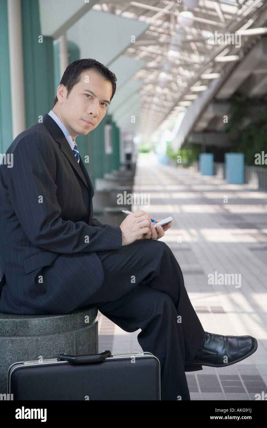 Portrait of a businessman sitting and using a palmtop Stock Photo