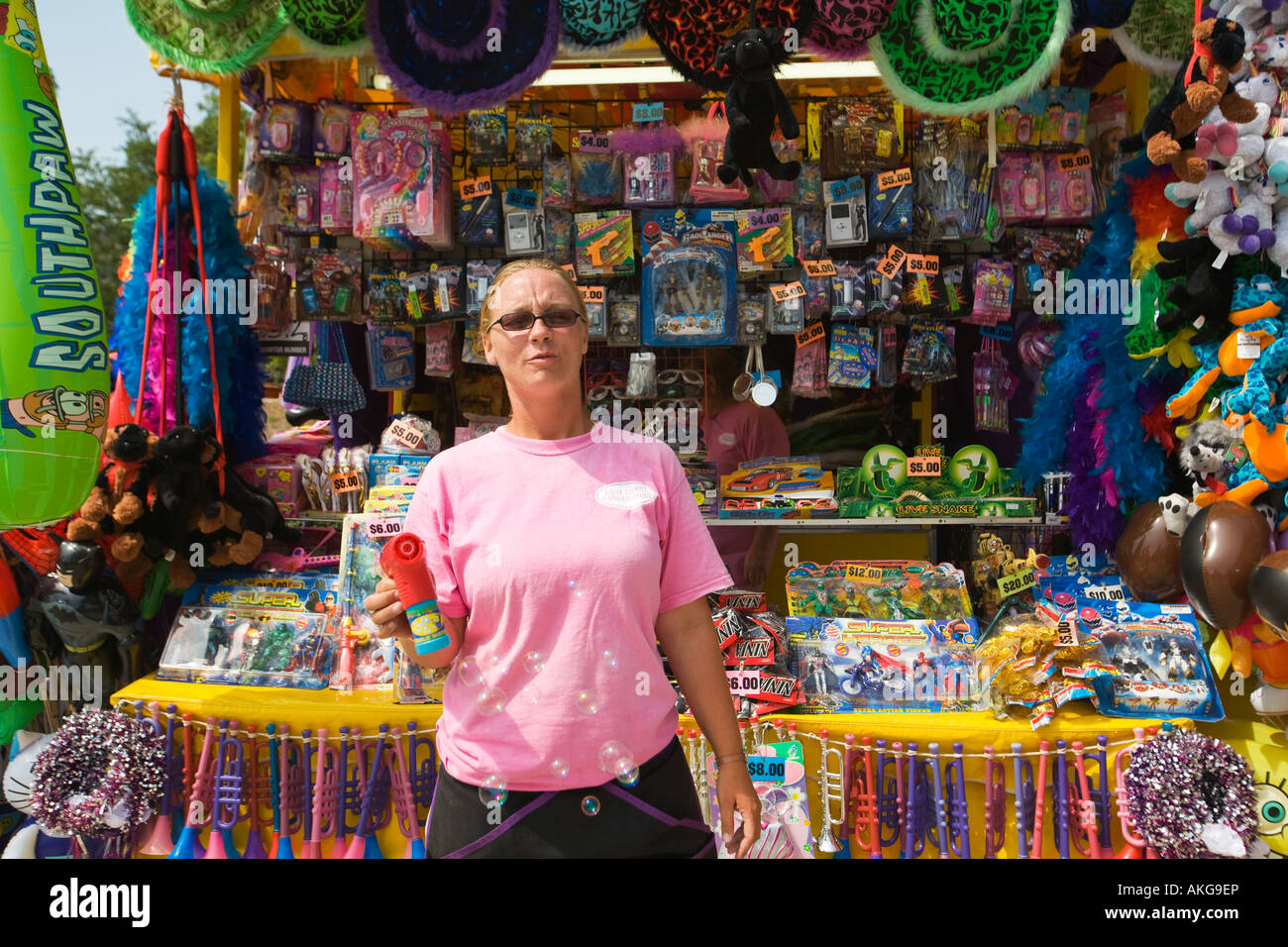 WISCONSIN Milwaukee Female carnival vendor blow bubbles with machine knick knacks and items for sale displayed Stock Photo