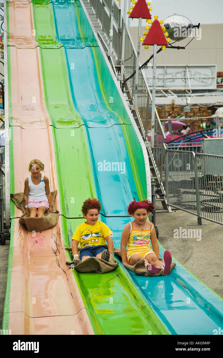 WISCONSIN Milwaukee Three children ride burlap sacks down big slide two have colored hair Stock Photo