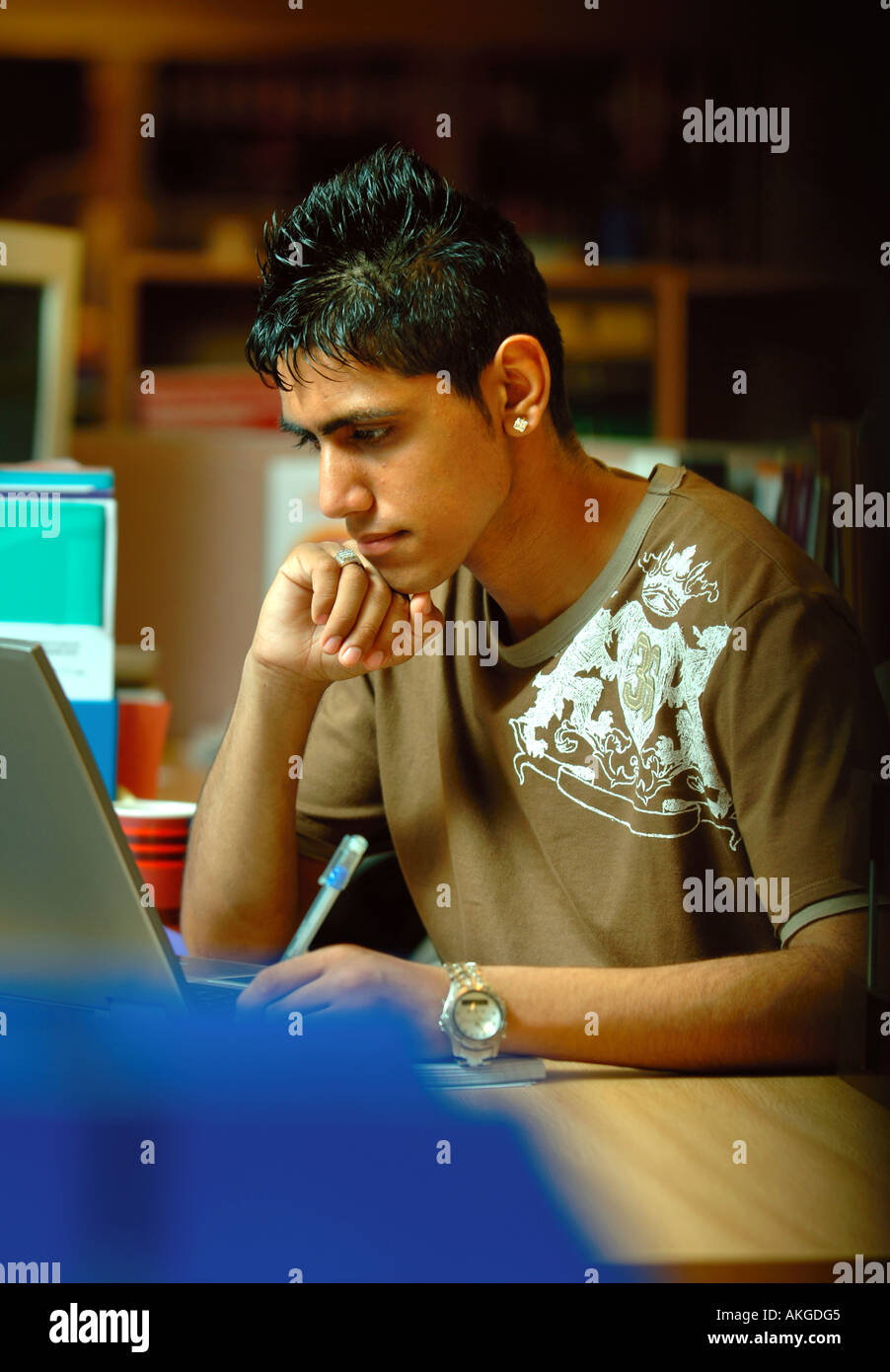 A TEENAGE BOY WORKING ON A LAPTOP COMPUTER IN AN OFFICE ENVIRONMENT UK ...