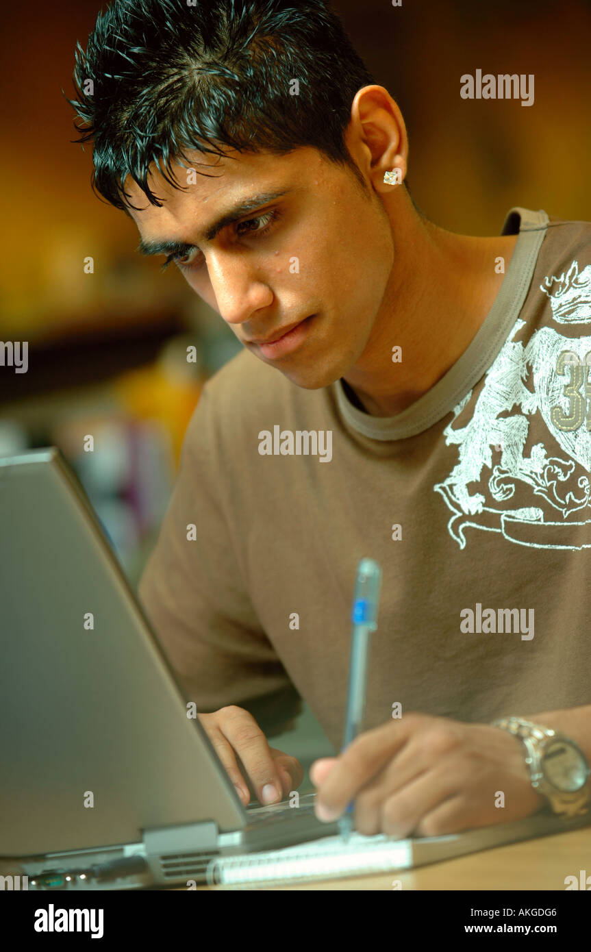 A TEENAGE BOY WORKING ON A LAPTOP COMPUTER IN AN OFFICE ENVIRONMENT UK ...