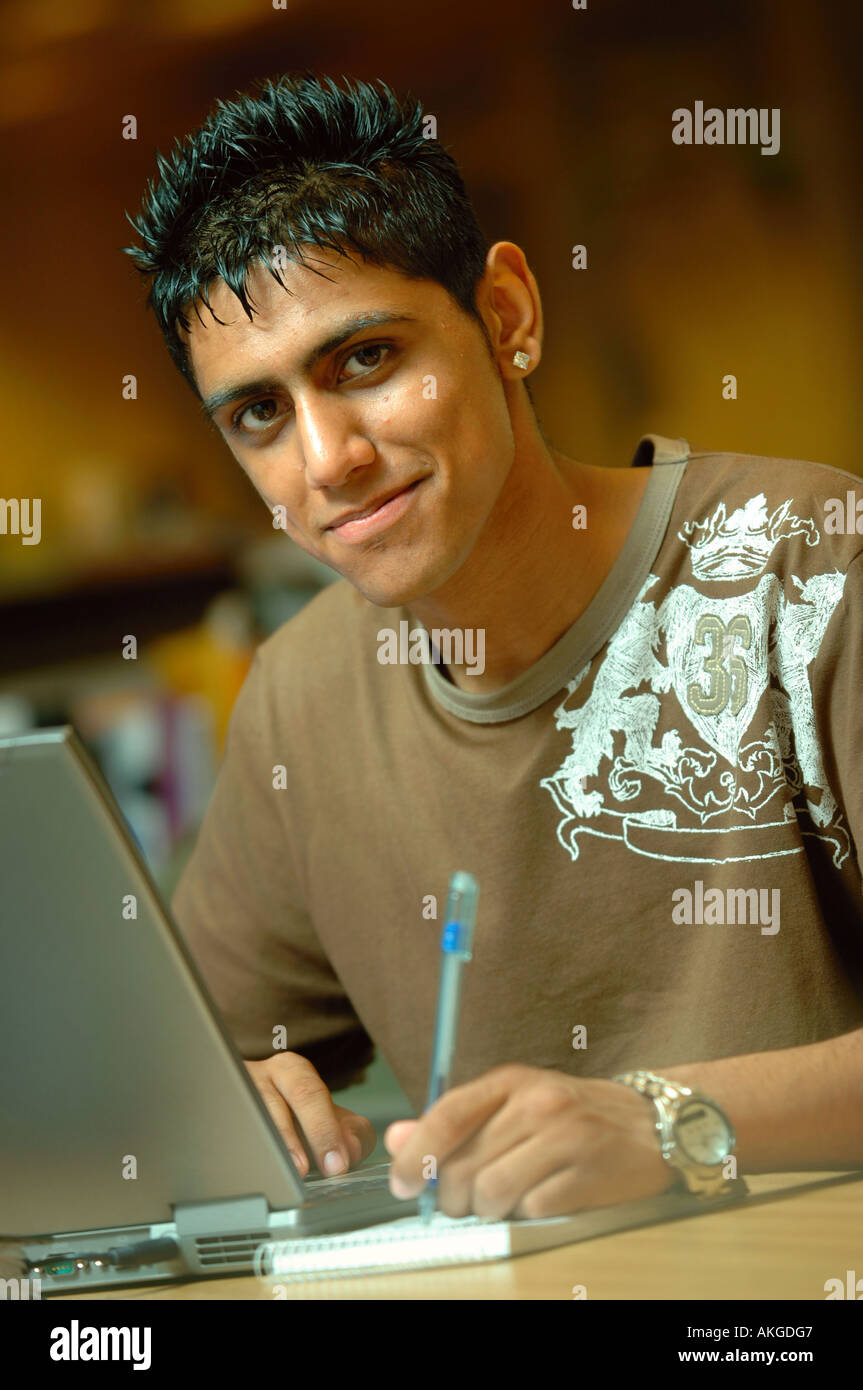 A TEENAGE BOY WORKING ON A LAPTOP COMPUTER IN AN OFFICE ENVIRONMENT UK ...