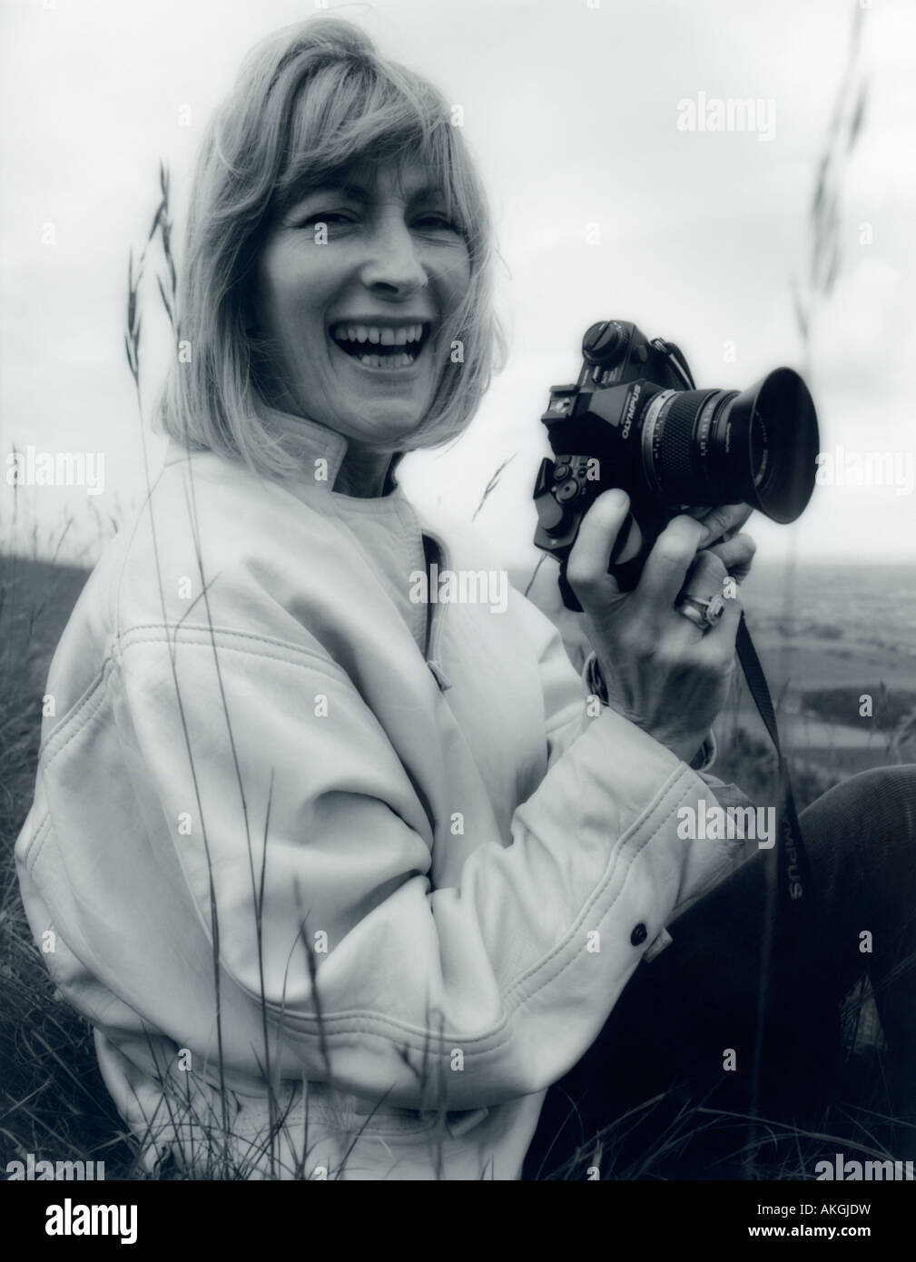 Candid portrait of woman holding SLR camera. Black and white photo, 1980s. Stock Photo