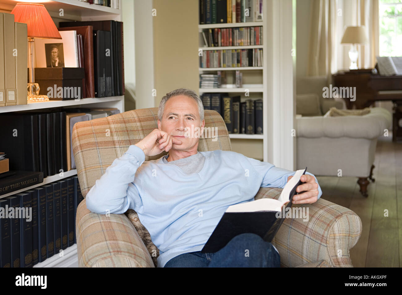 Man in an arm chair with book Stock Photo Alamy