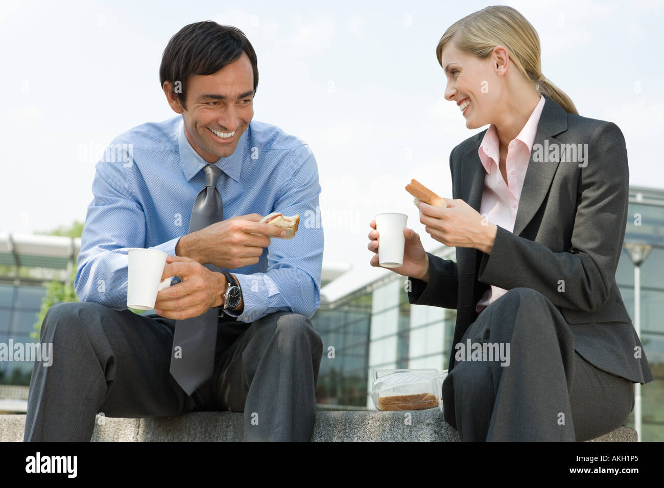 Businesswoman and businessman eating sandwiches outdoors Stock Photo