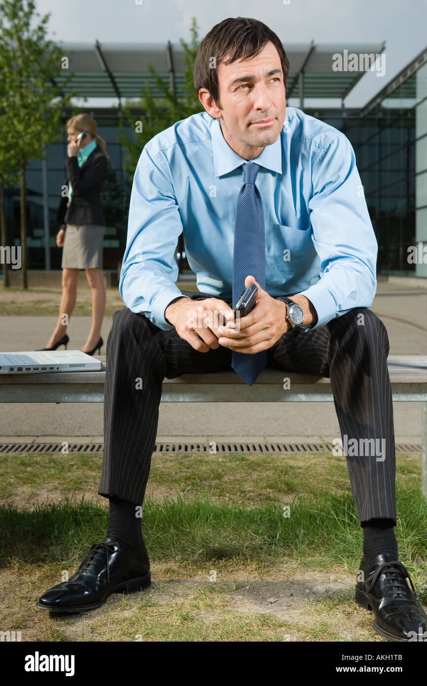 Businessman sitting on bench outdoors Stock Photo