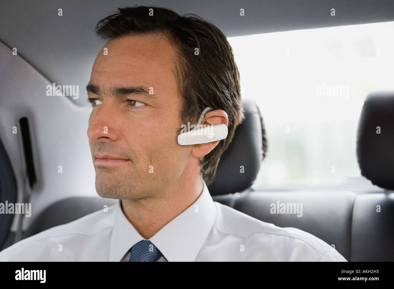 Businessman with bluetooth headset sitting in car Stock Photo