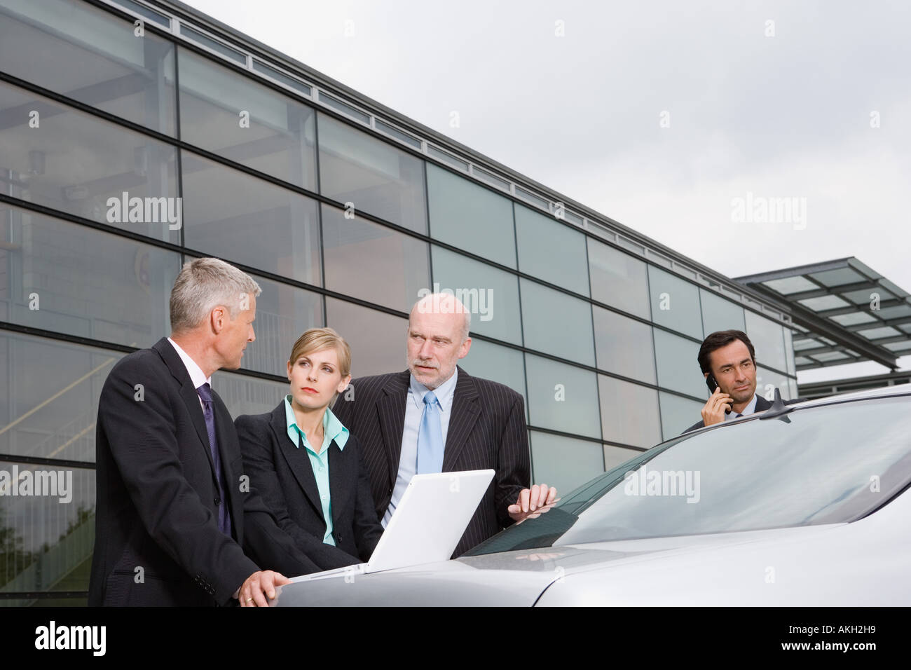 Businesspeople looking at laptop on automobile boot Stock Photo