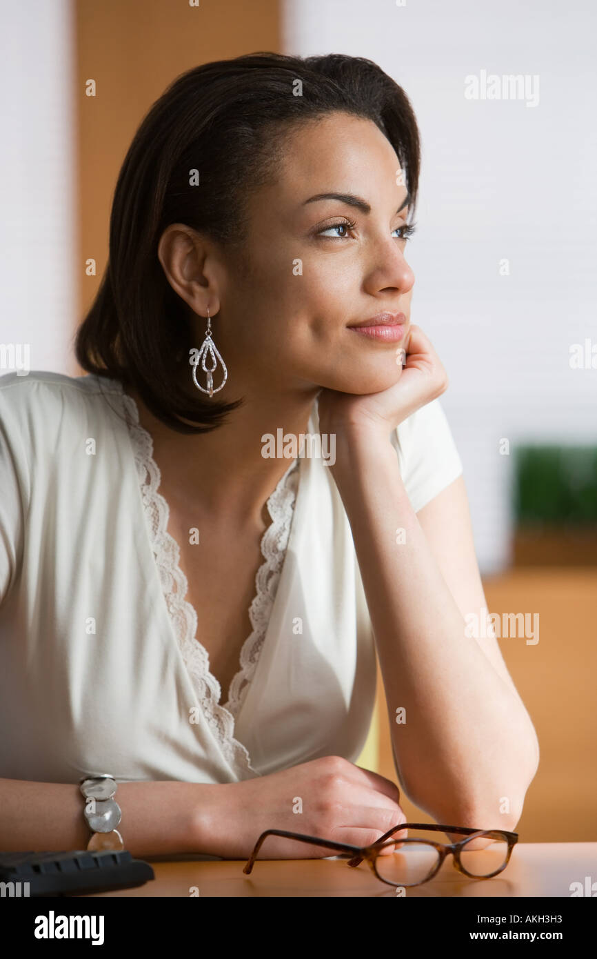 Pensive woman sitting at table Stock Photo
