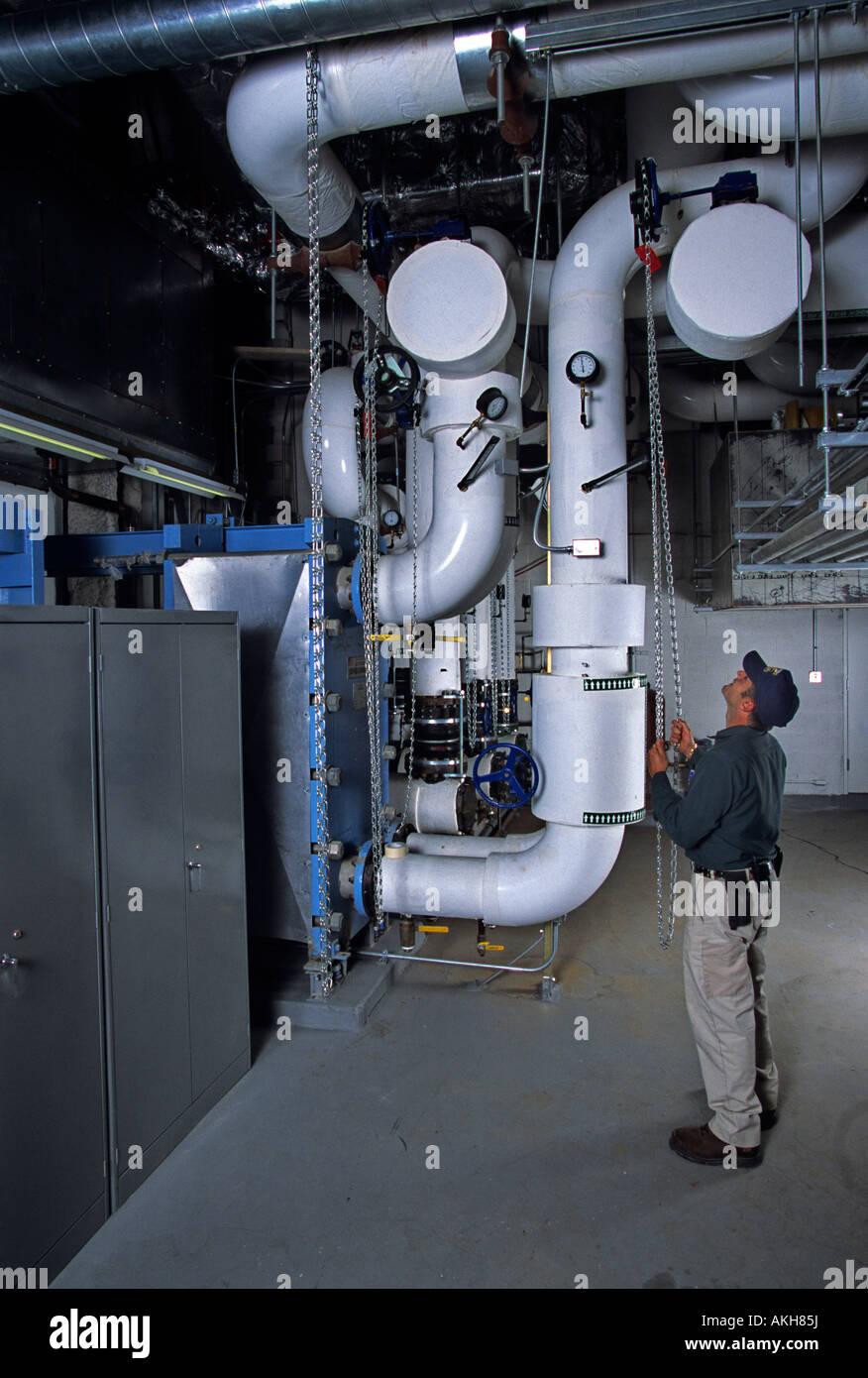 Worker and pipes for boiler in climate control system in new skyscraper Stock Photo
