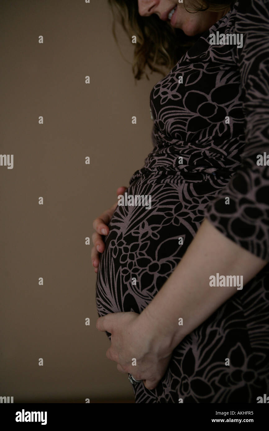 Pregnant woman holding her stomach Stock Photo - Alamy
