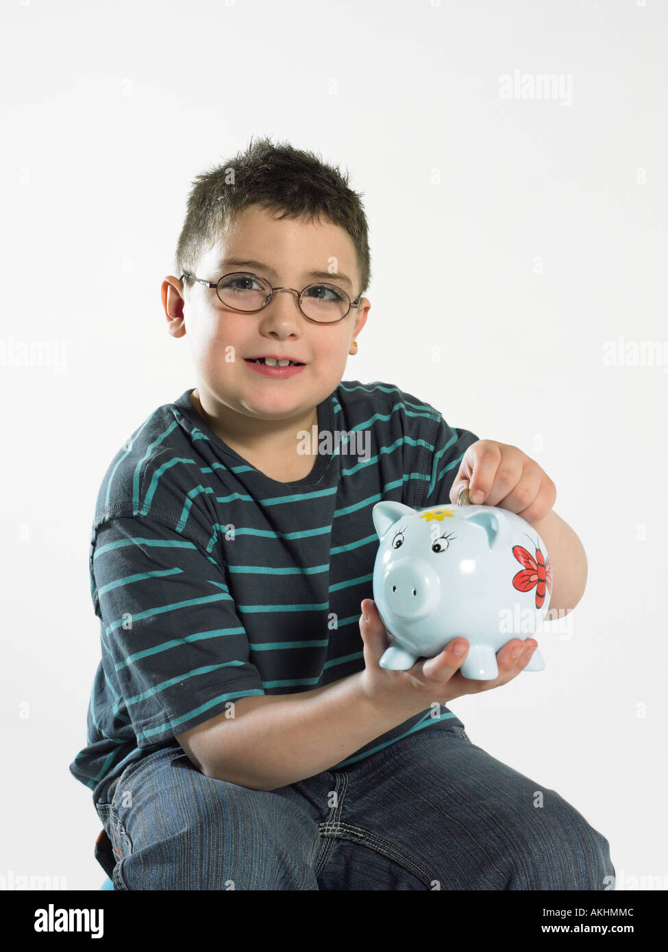 Boy putting coin in piggy bank Stock Photo - Alamy