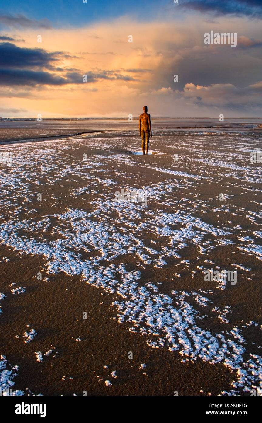 Antony Gormley Iron man statue on Crosby beach, Sefton, Merseyside Uk, at sunrise. With previous nights snow. Stock Photo
