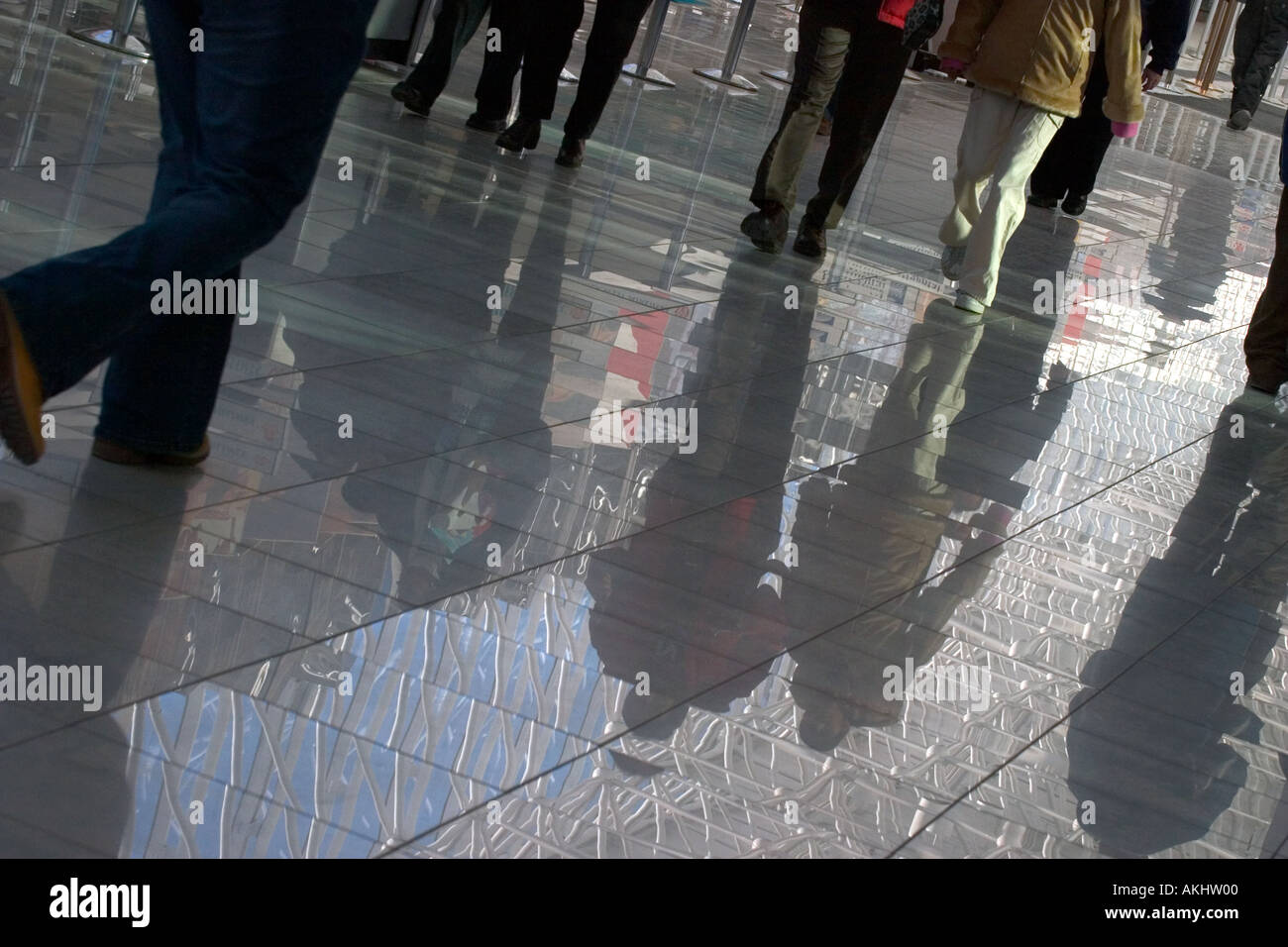Reflection in a shiny floor of anonymous people rushing and hurrying ...