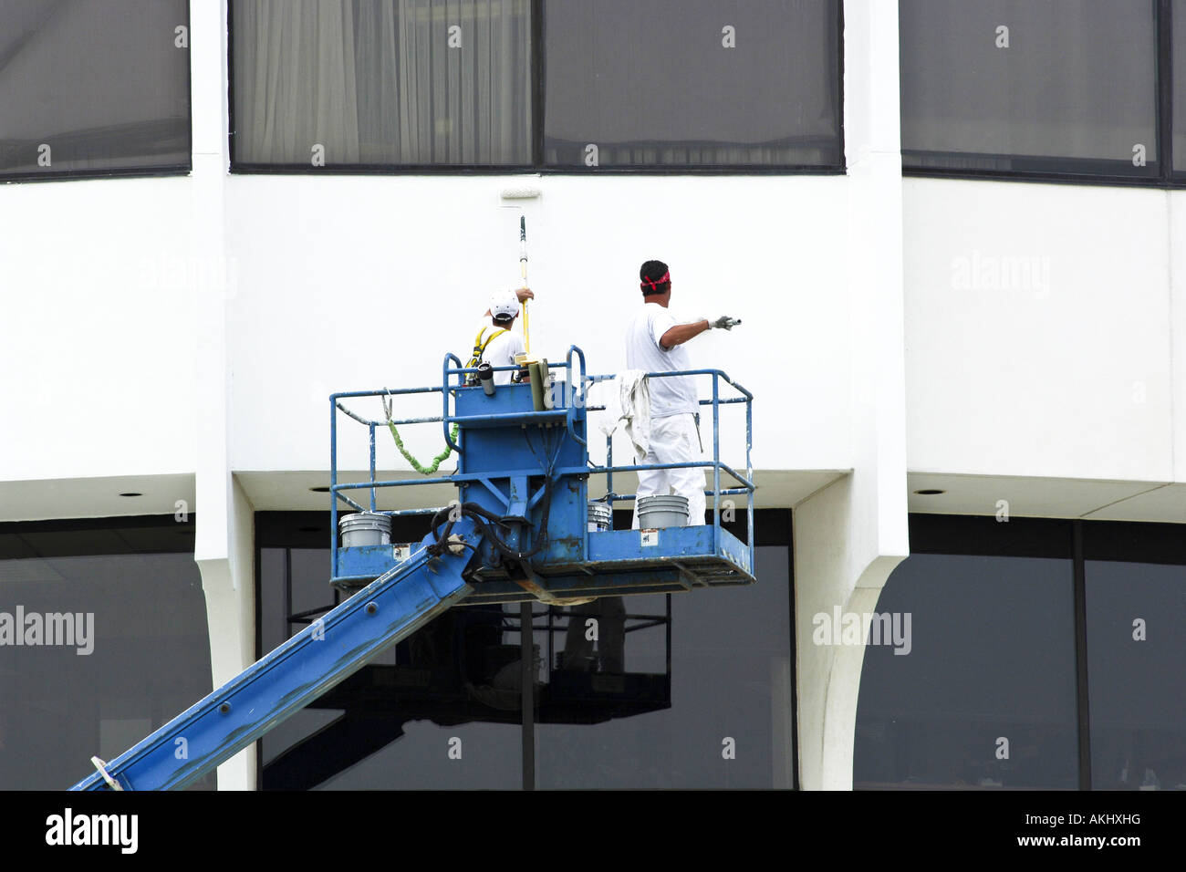 Painters busily working on a white building using a portable lift Stock Photo