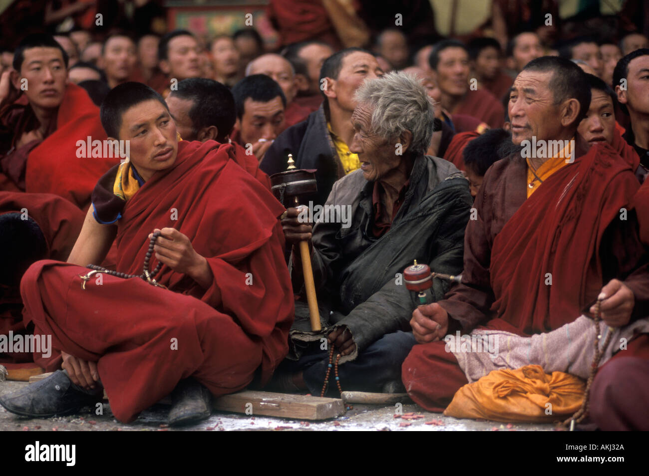 Ningma monks and Khampa with prayer wheel at the Monlam Chenmo Katok Monastery Kham Tibet Sichuan China Stock Photo