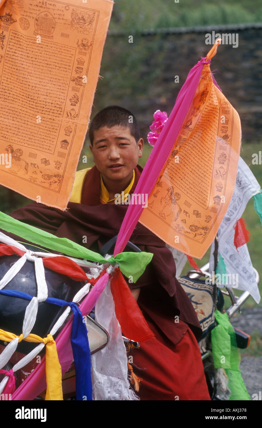 Buddhist monk with motorcycle decorated with katoks and prayer flags Kham E Tibet Sichuan Province China Stock Photo