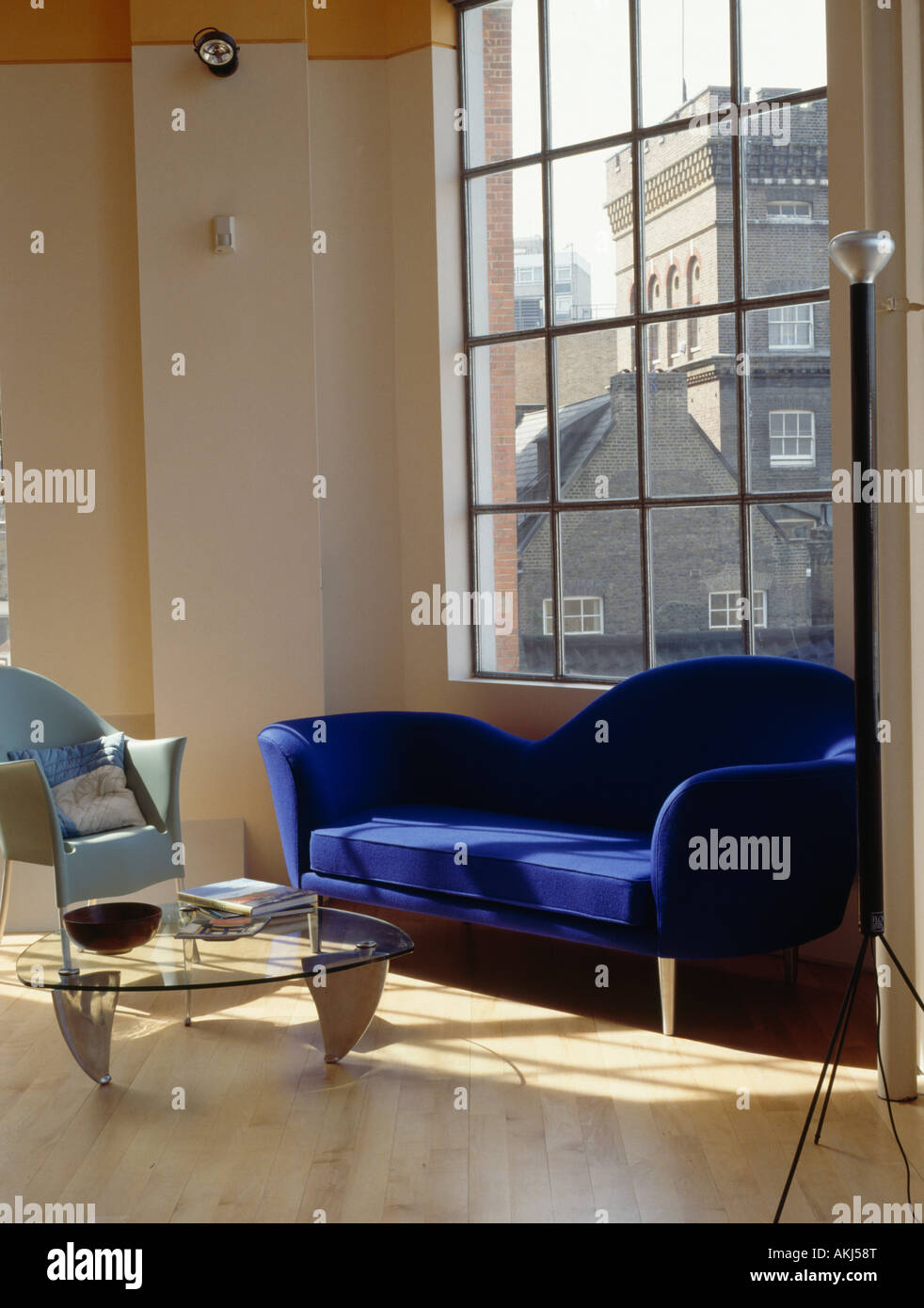 Modern blue sofa in front of large window in living room in converted loft with wooden flooring