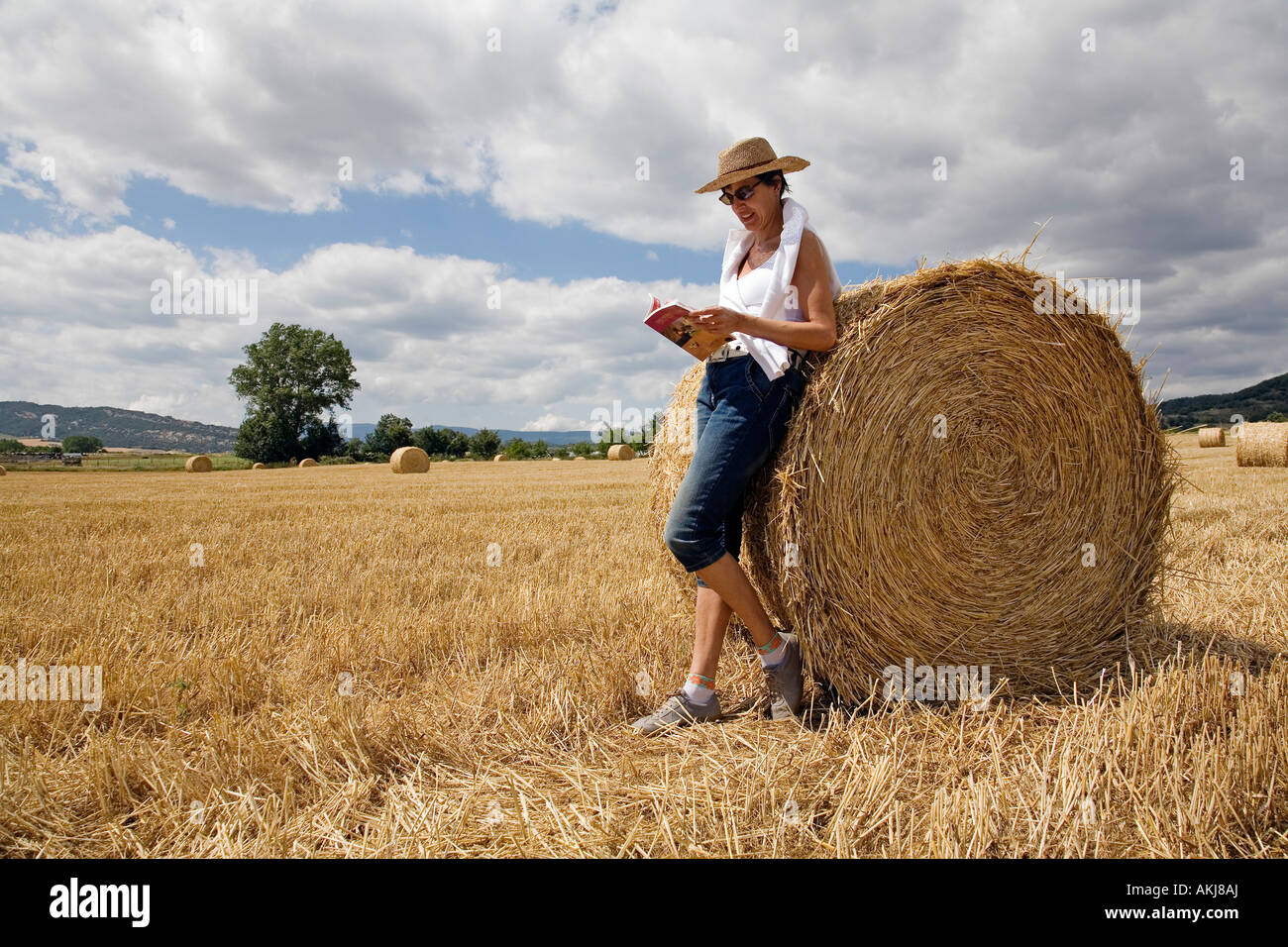 Women reading about a roll of straw packed in a wheat field just cut