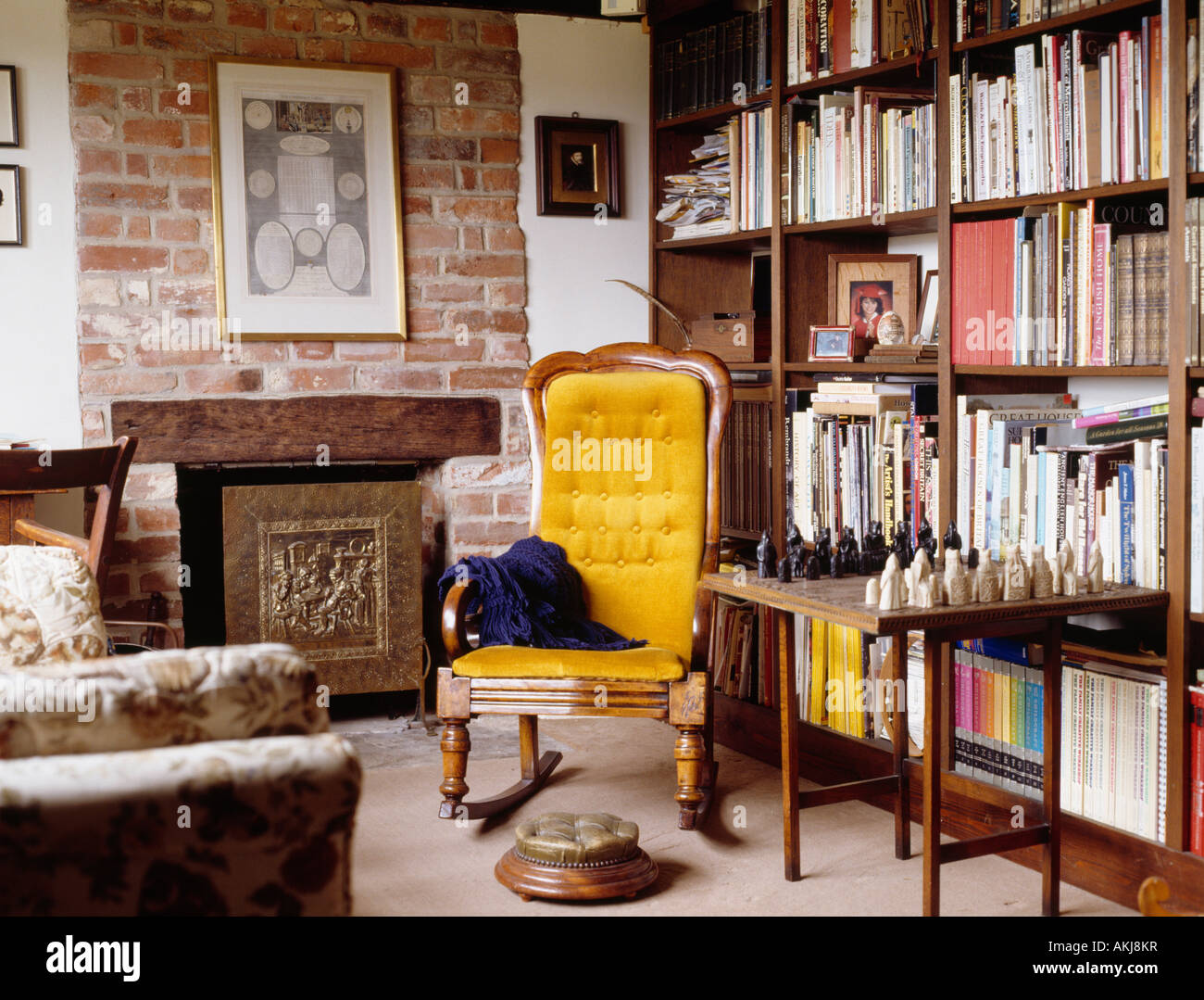 Yellow armchair and chess set on table in front of bookshelves in ...