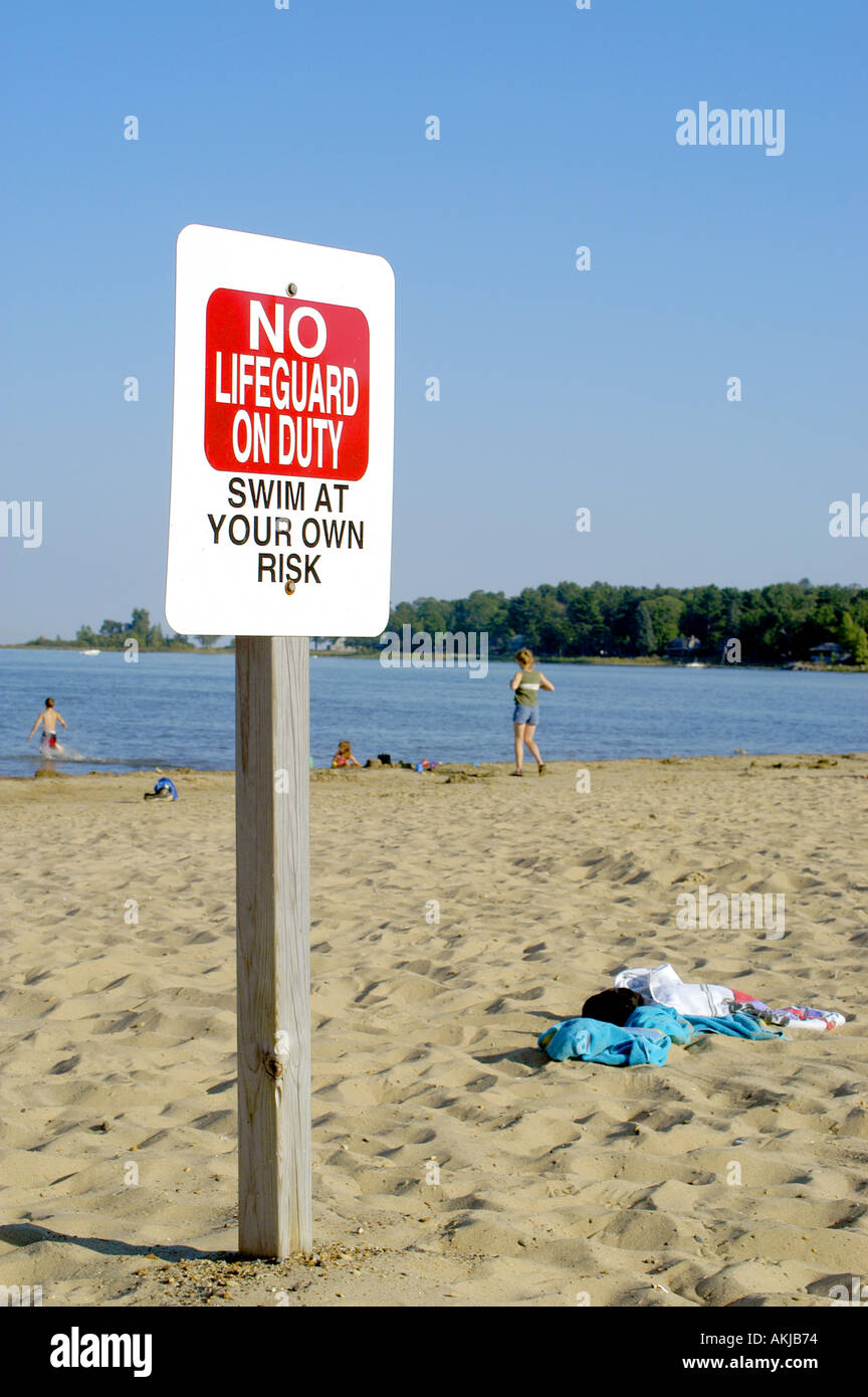 Sign on public beach states No life guard on duty swim at own risk Stock Photo