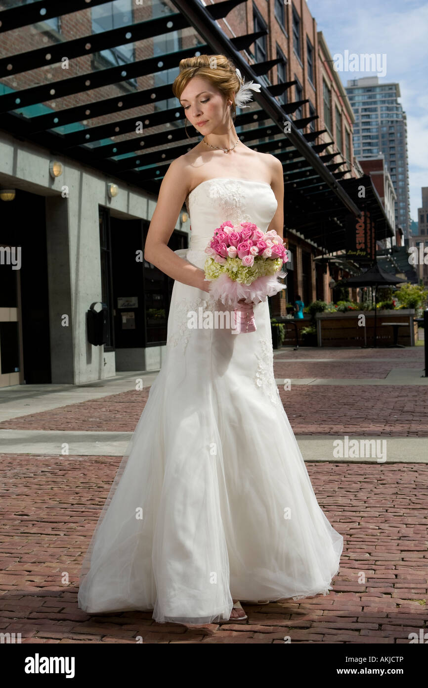 a beautiful bride in a white wedding dress holding her flower bouquet ...