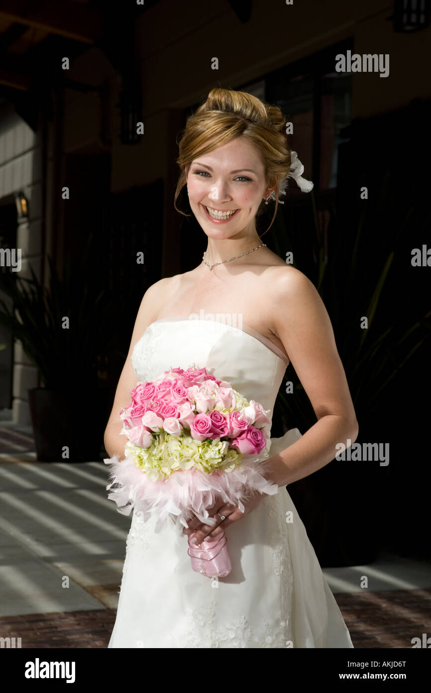 a beautiful bride in a white wedding dress holding her flower bouquet ...