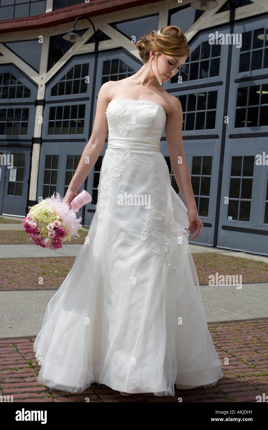 a beautiful bride in a white wedding dress holding her flower bouquet ...