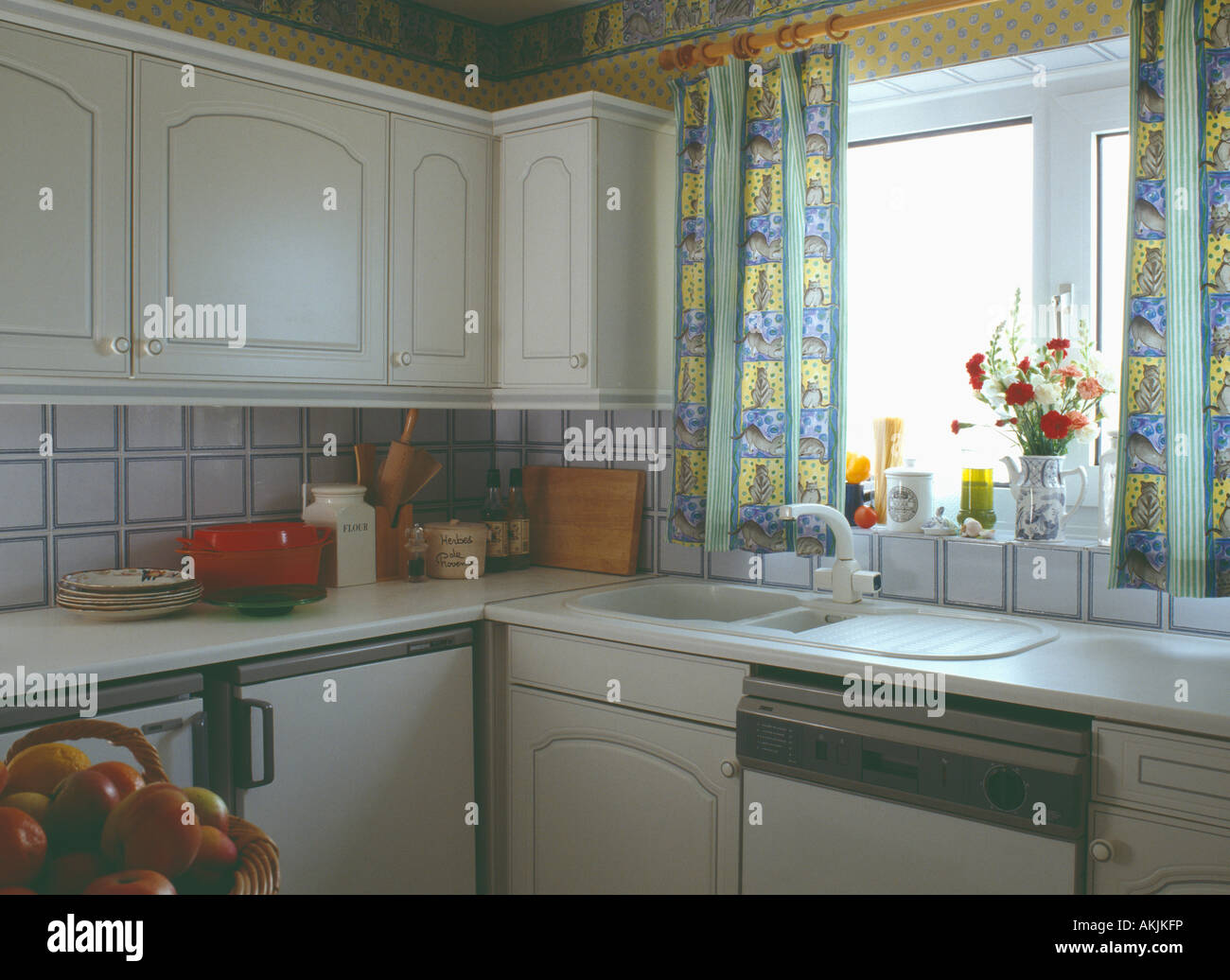 https://c8.alamy.com/comp/AKJKFP/yellow-patterned-curtains-above-white-sink-in-small-nineties-kitchen-AKJKFP.jpg
