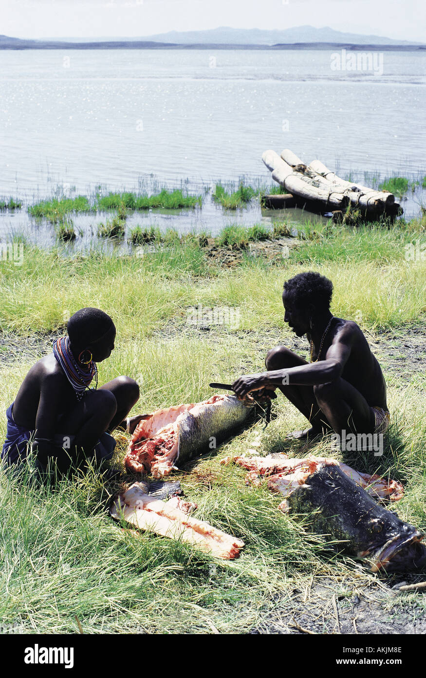 El Molo man and his wife cutting up a huge Nile Perch which he has caught using a harpoon Stock Photo