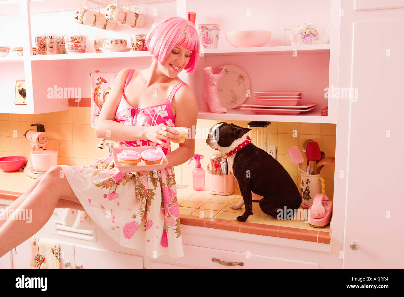 Woman in retro kitchen with dog and cupcakes Stock Photo