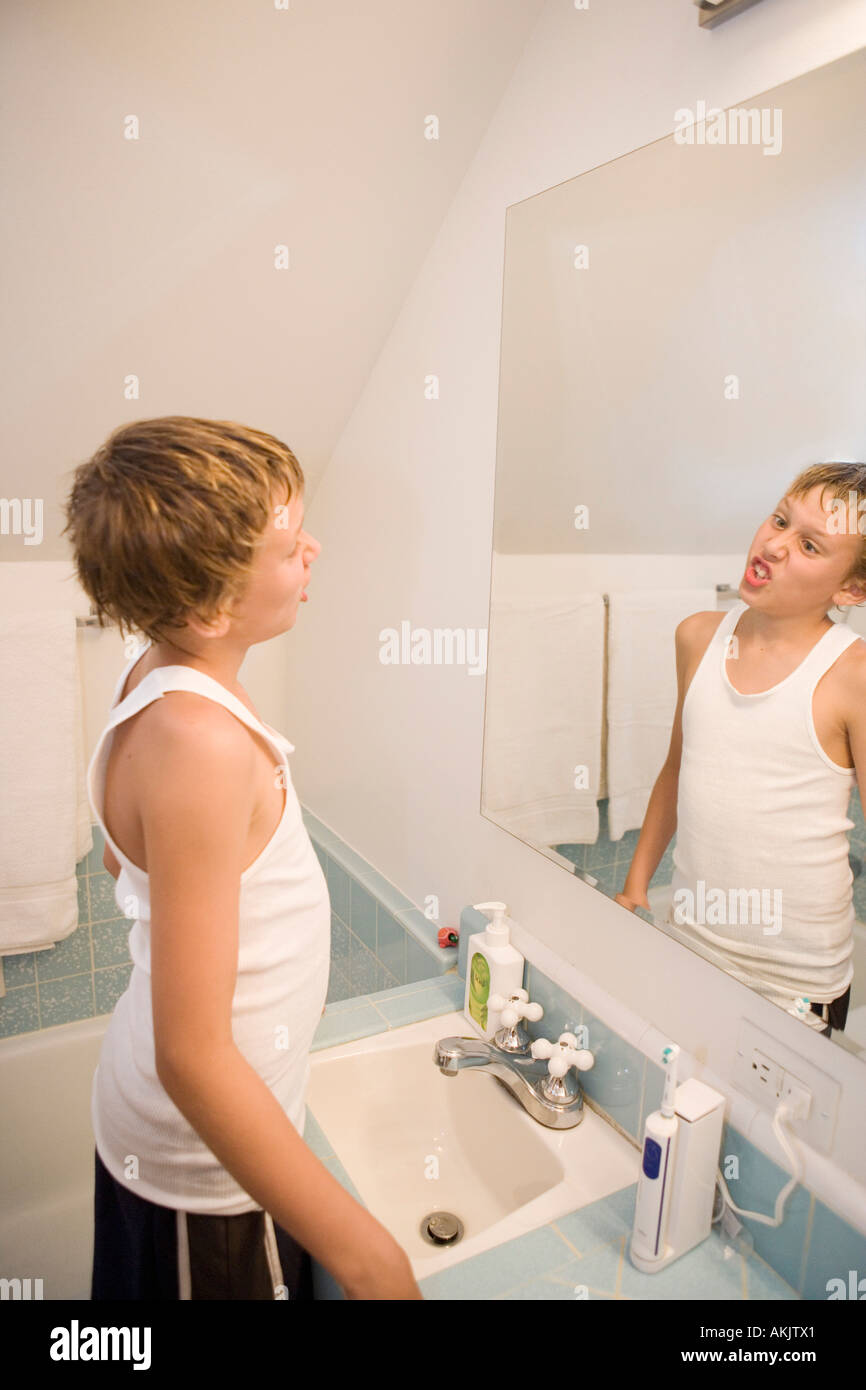 Boy making faces in bathroom mirror Stock Photo