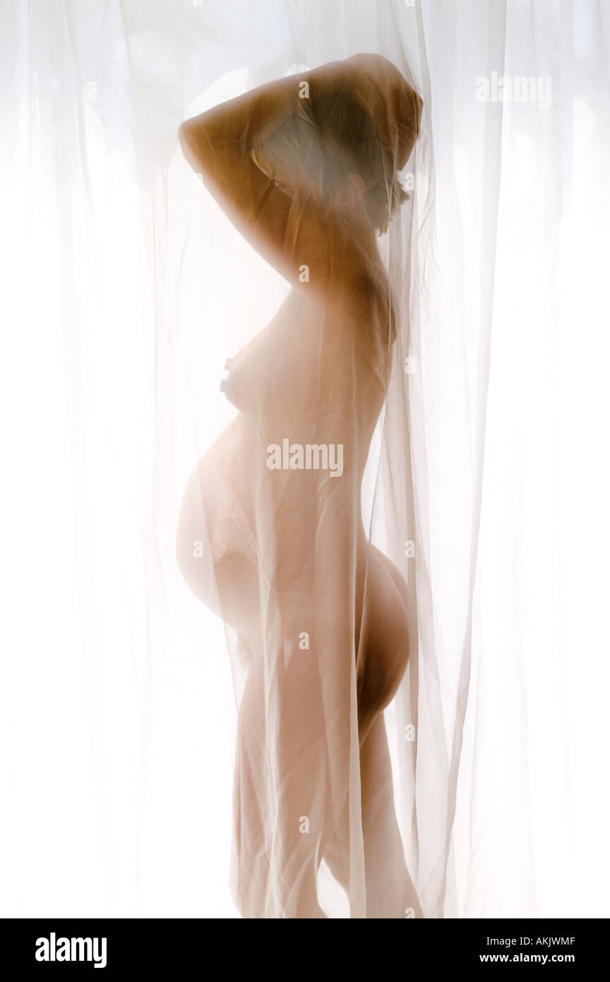 Profile of nude pregnant woman behind curtain Stock Photo