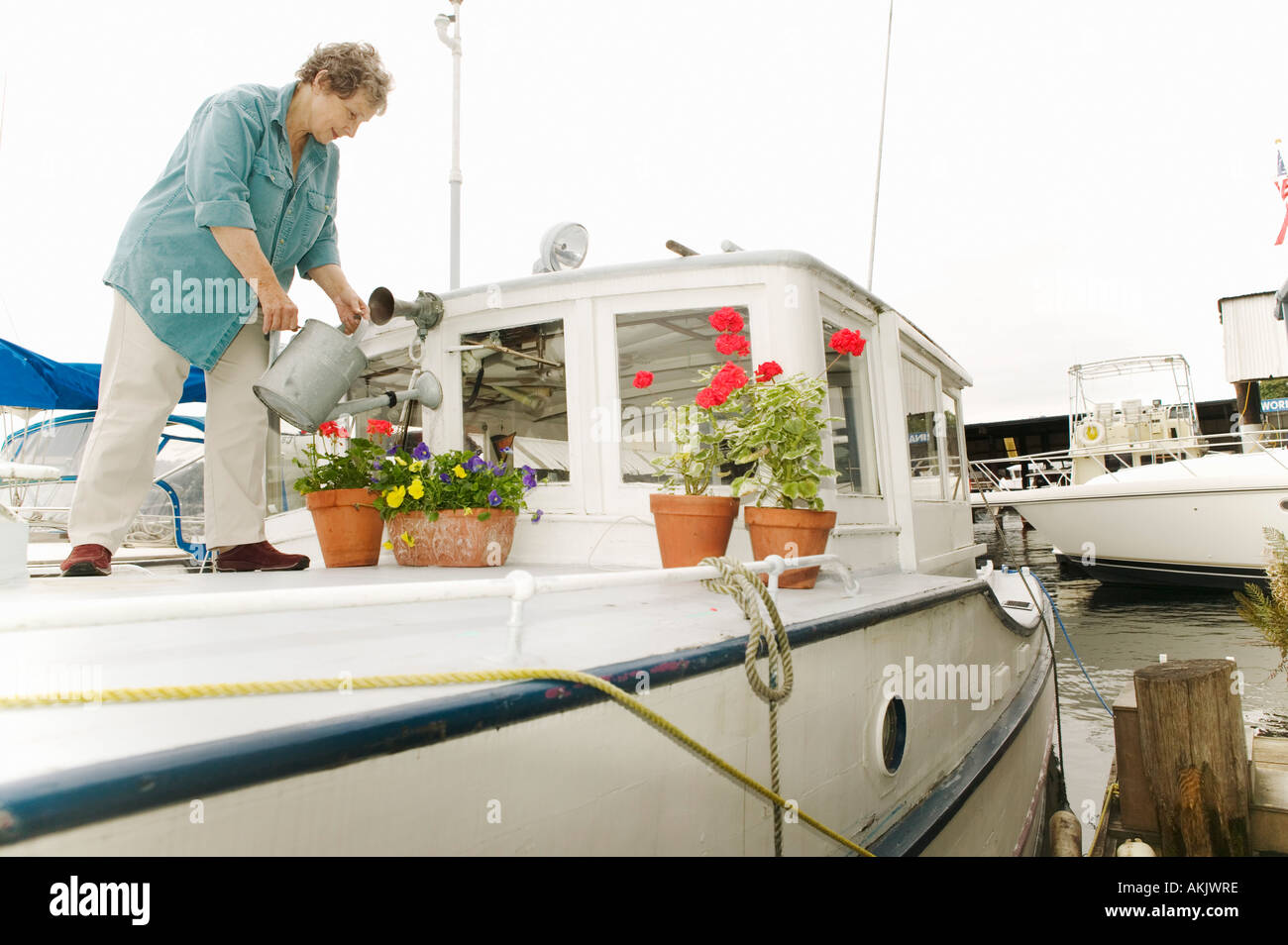 Woman watering plants on houseboat Stock Photo