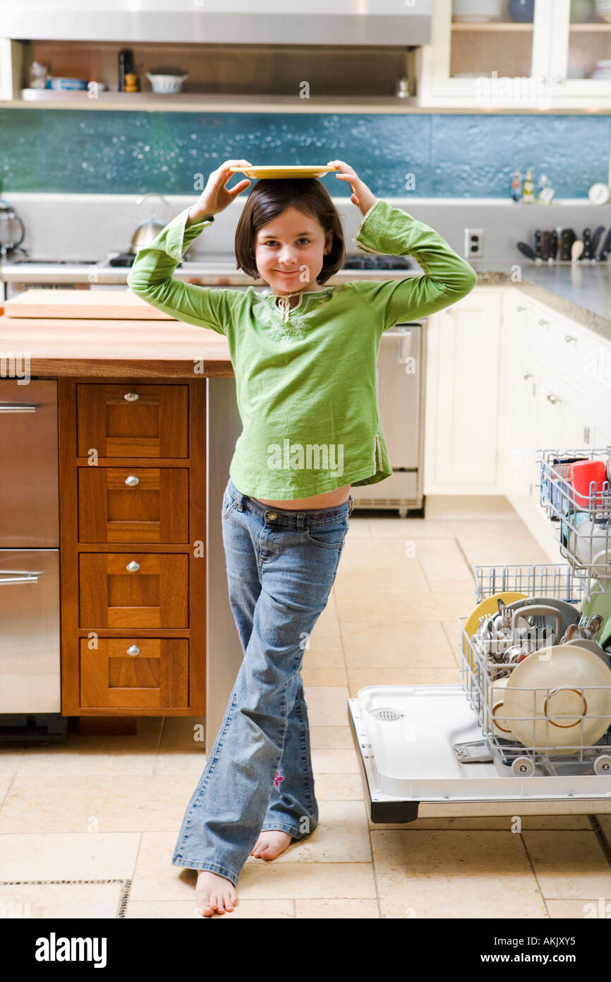 Girl balancing plate on head in kitchen Stock Photo Alamy