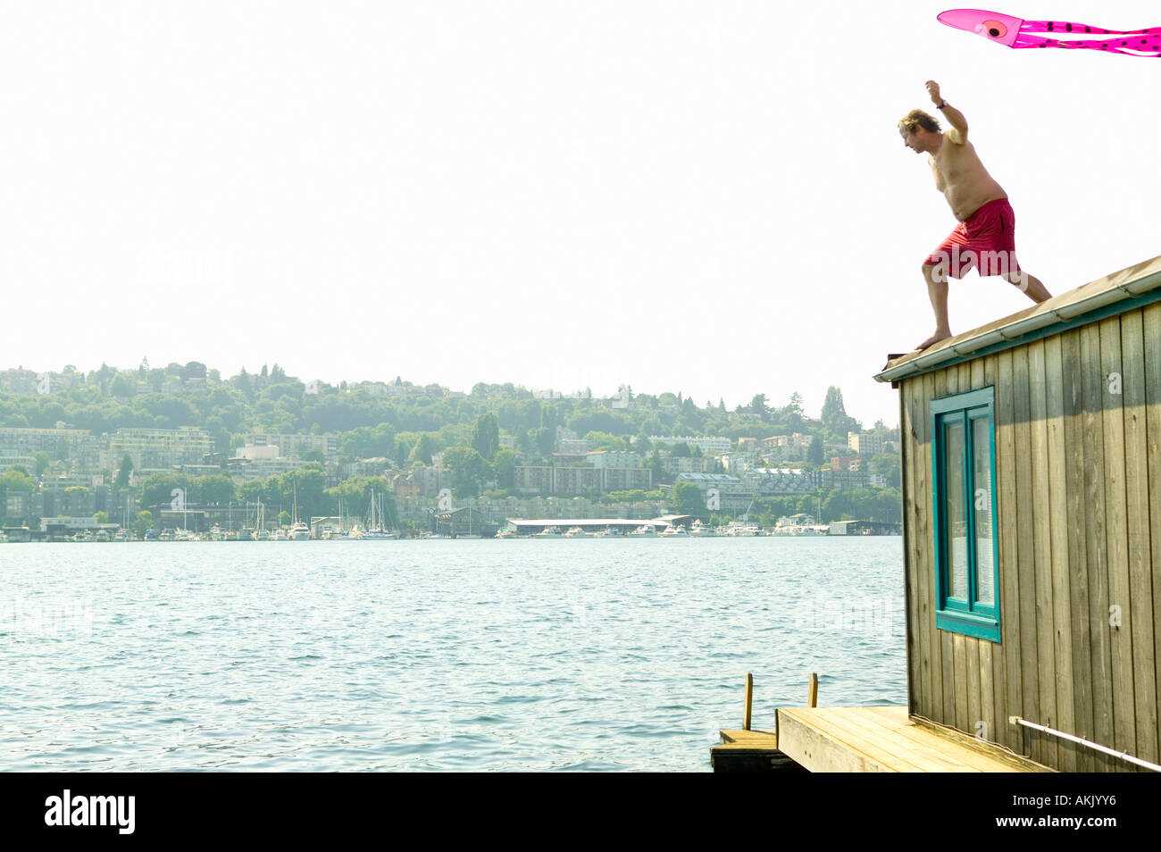 Man on roof of houseboat with kite Stock Photo