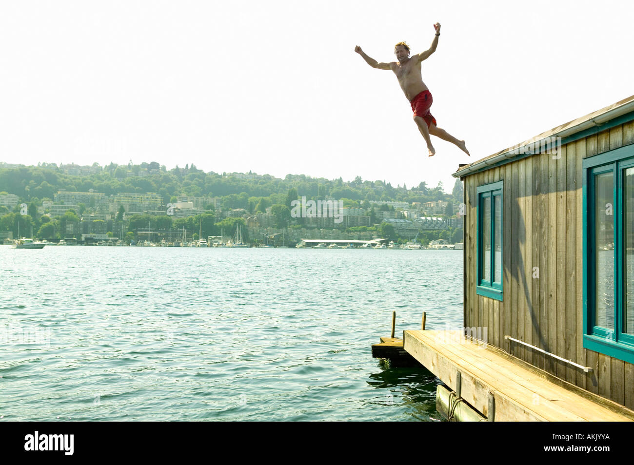 Man jumping into water from houseboat roof Stock Photo