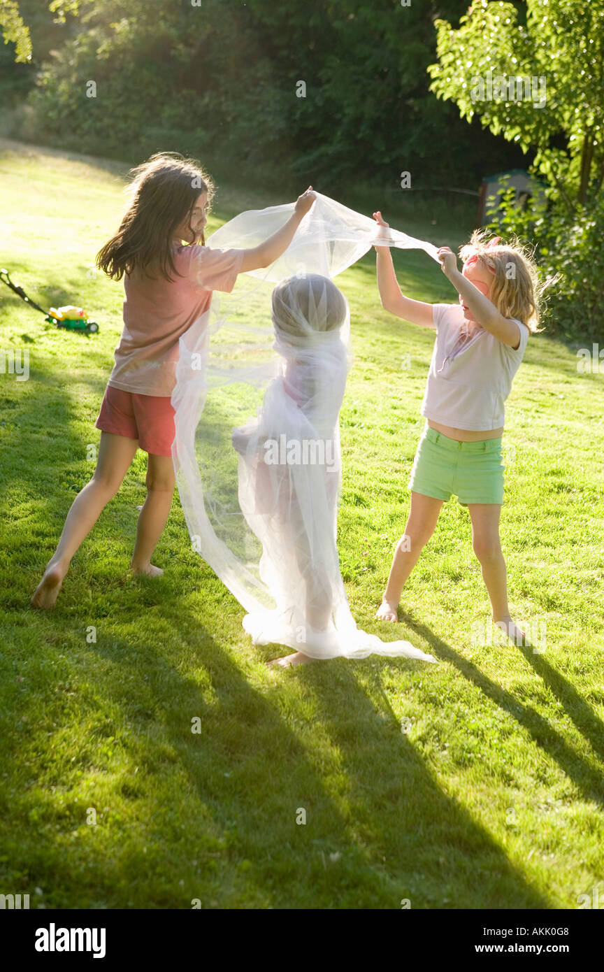 Young girls wrapping friend in fabric outdoors Stock Photo