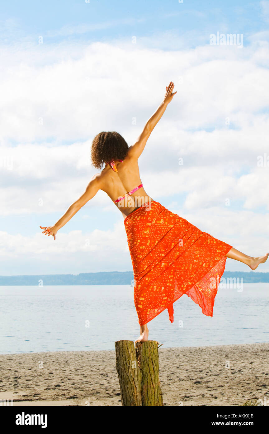 Woman balancing on log at beach Stock Photo