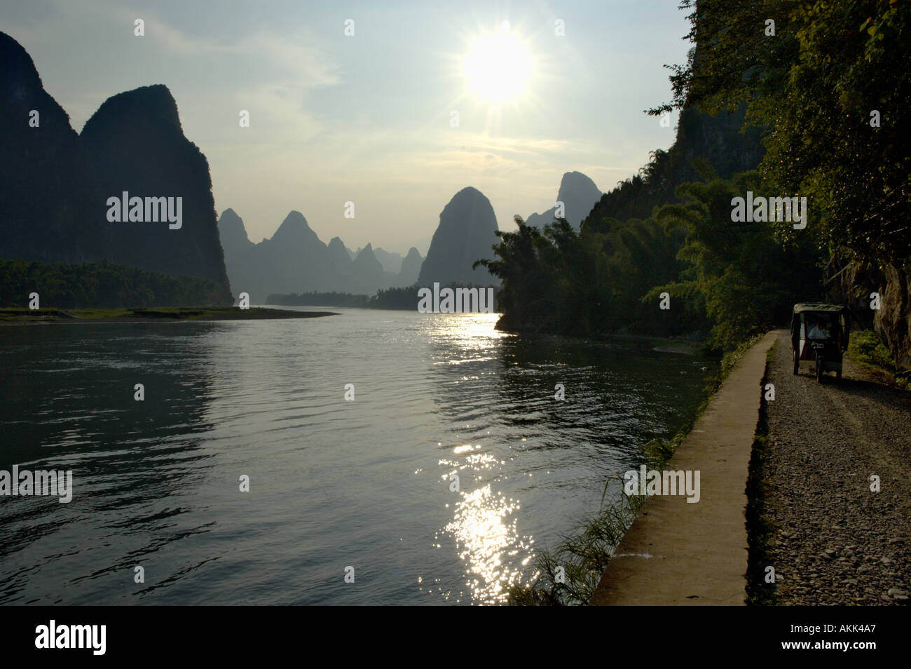 Lijiang or Li River at sunset with man in motor tricycle on the road - Yangshuo County, Guangxi, China Stock Photo