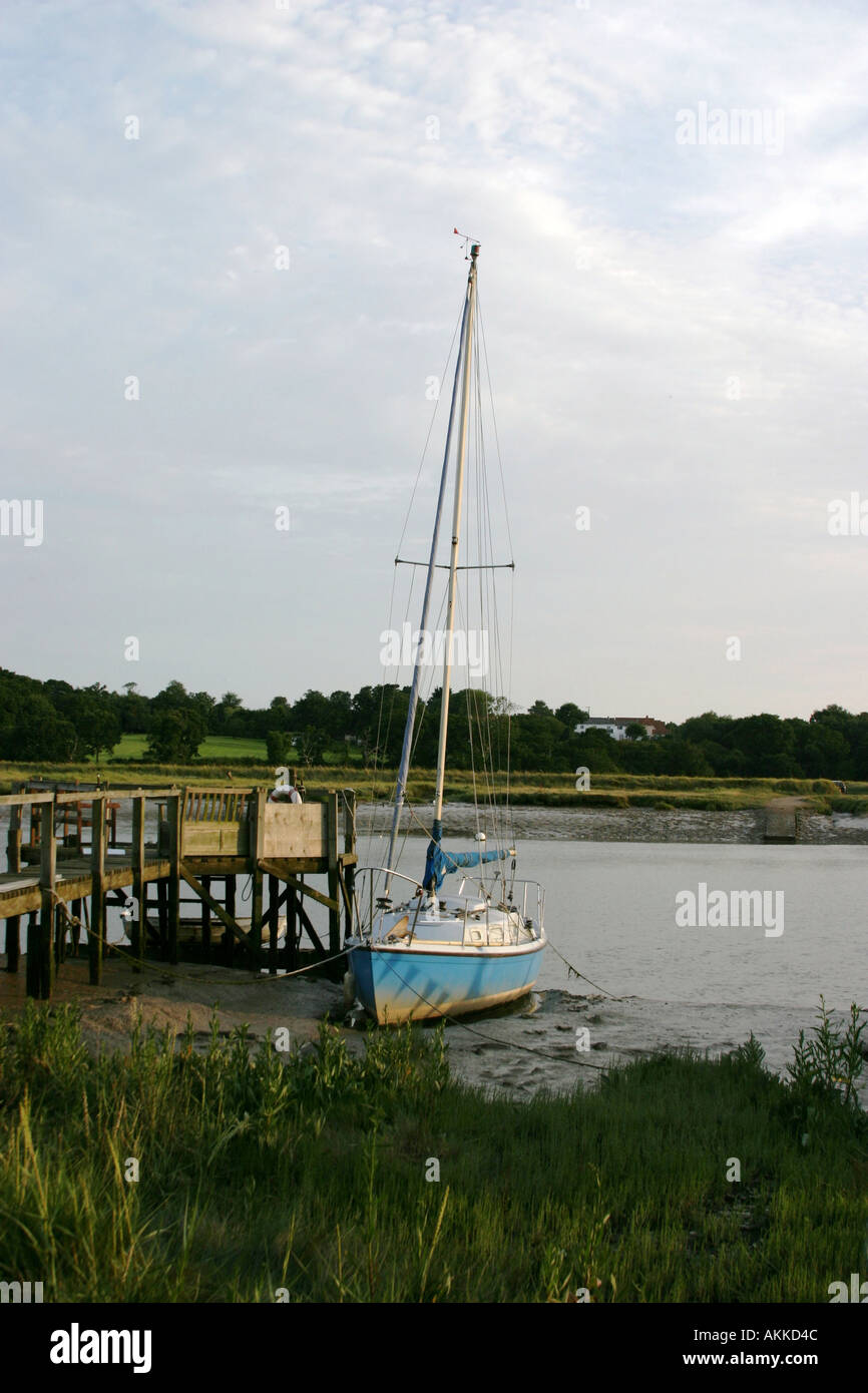 Boat on mudflats near jetty on River Colne Wivenhoe Essex UK Stock Photo