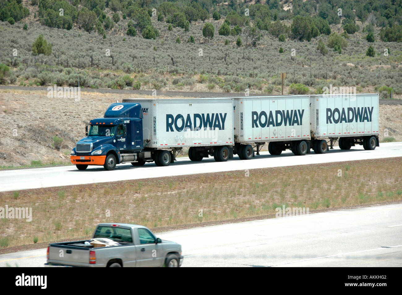 Commercial Trucks in highways roads freeways with cars triple three trailers on one tractor 3 trailers in America, USA, Western Stock Photo