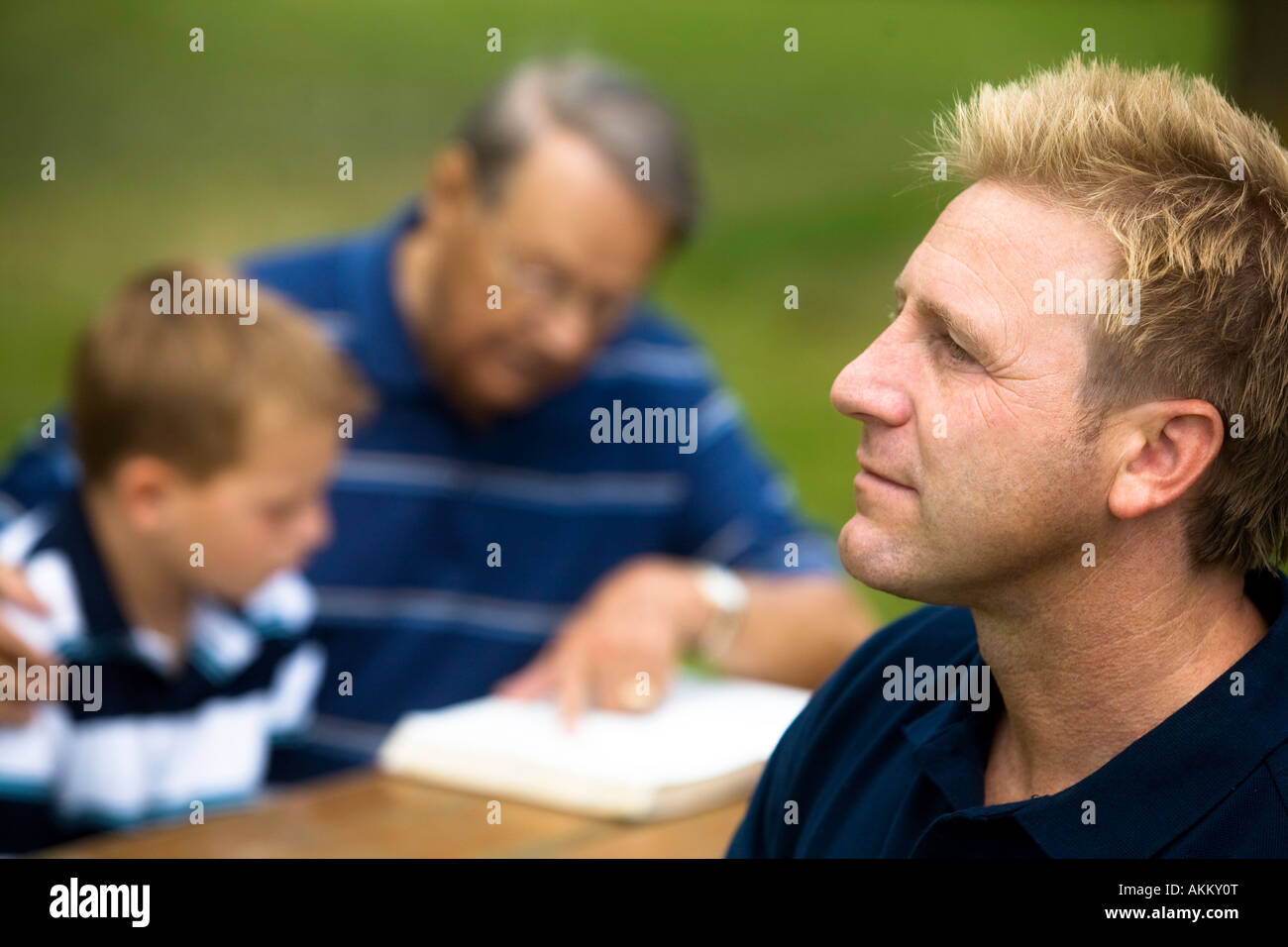 Man reflecting while his family is reading Stock Photo