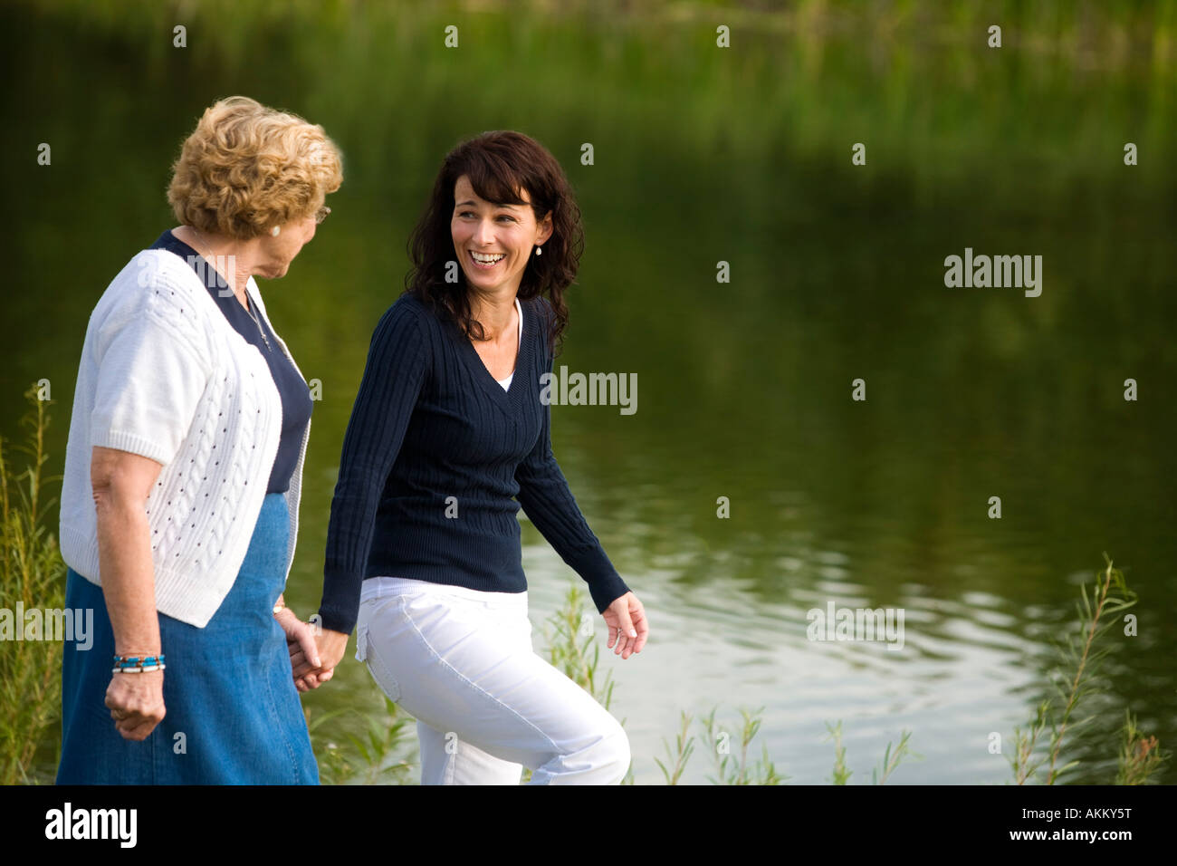 Two women walking beside a lake Stock Photo - Alamy